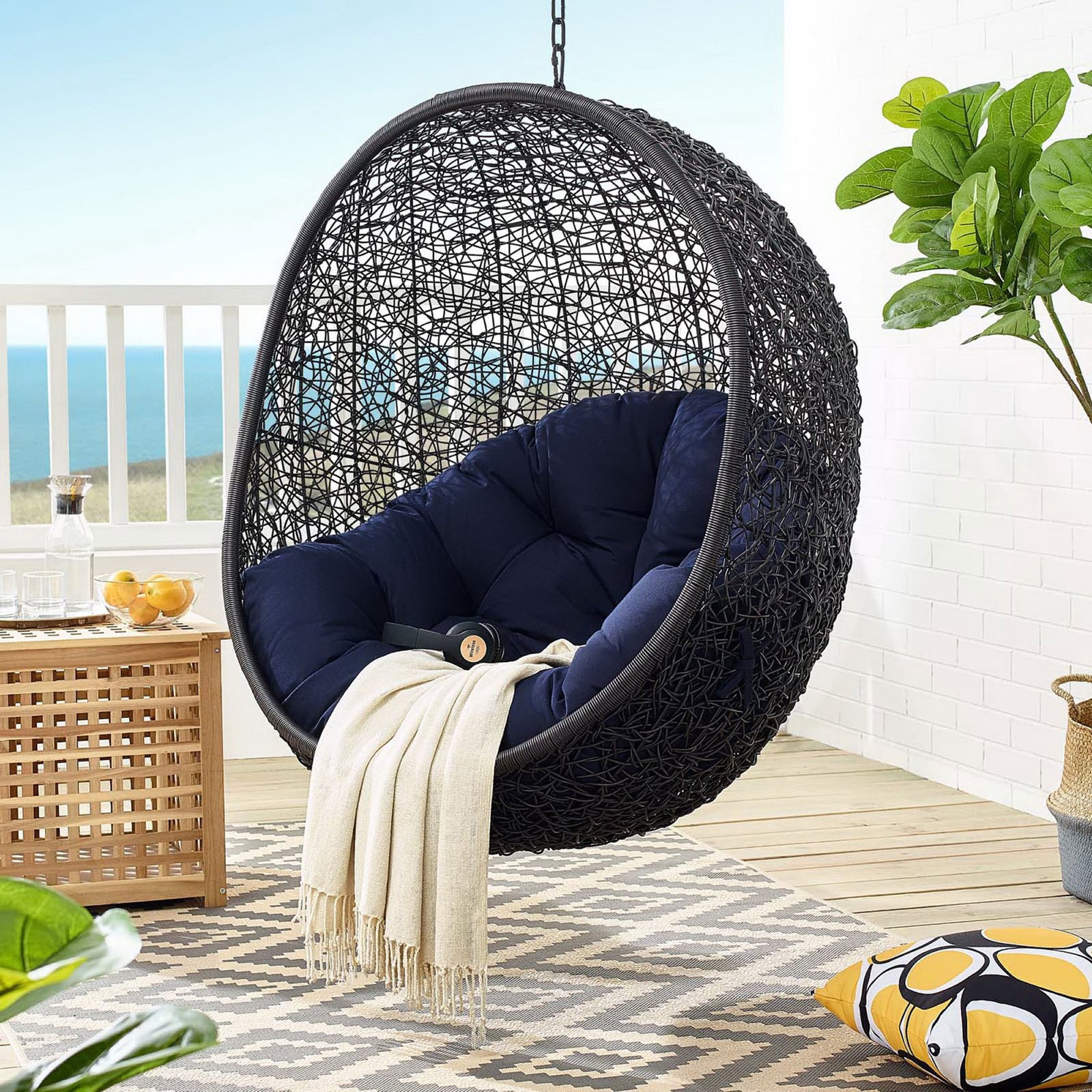 Suspended navy Sunbrella swing chair creating a relaxing retreat with ocean views and fresh air || EEI-3943-BLK-NAV || front_angle_partial_room