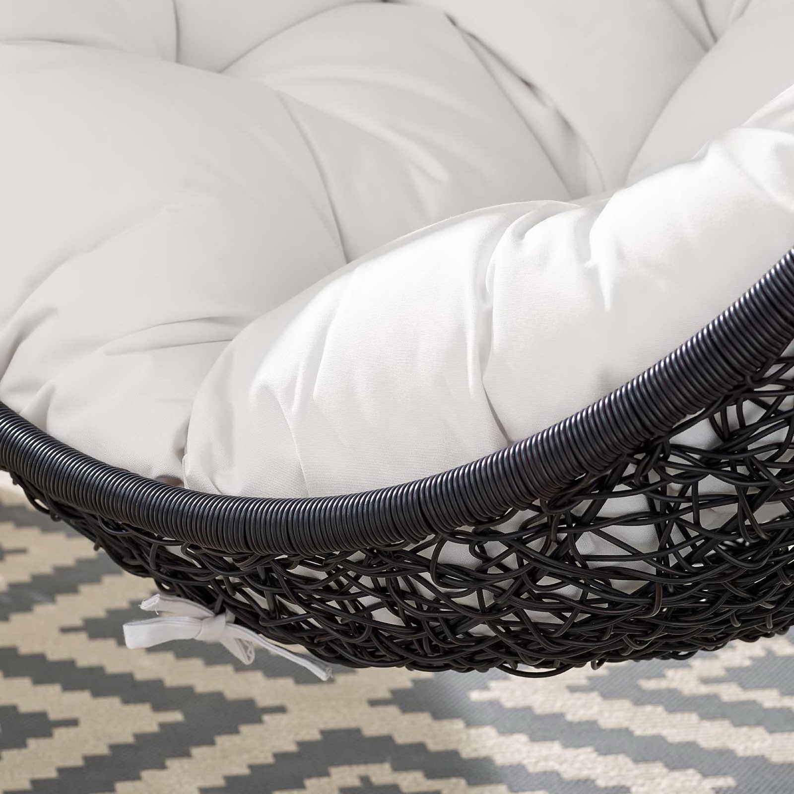Detail of white Sunbrella cushion on outdoor egg chair layered over a bold patterned rug || EEI-3943-BLK-WHI || swatch_room
