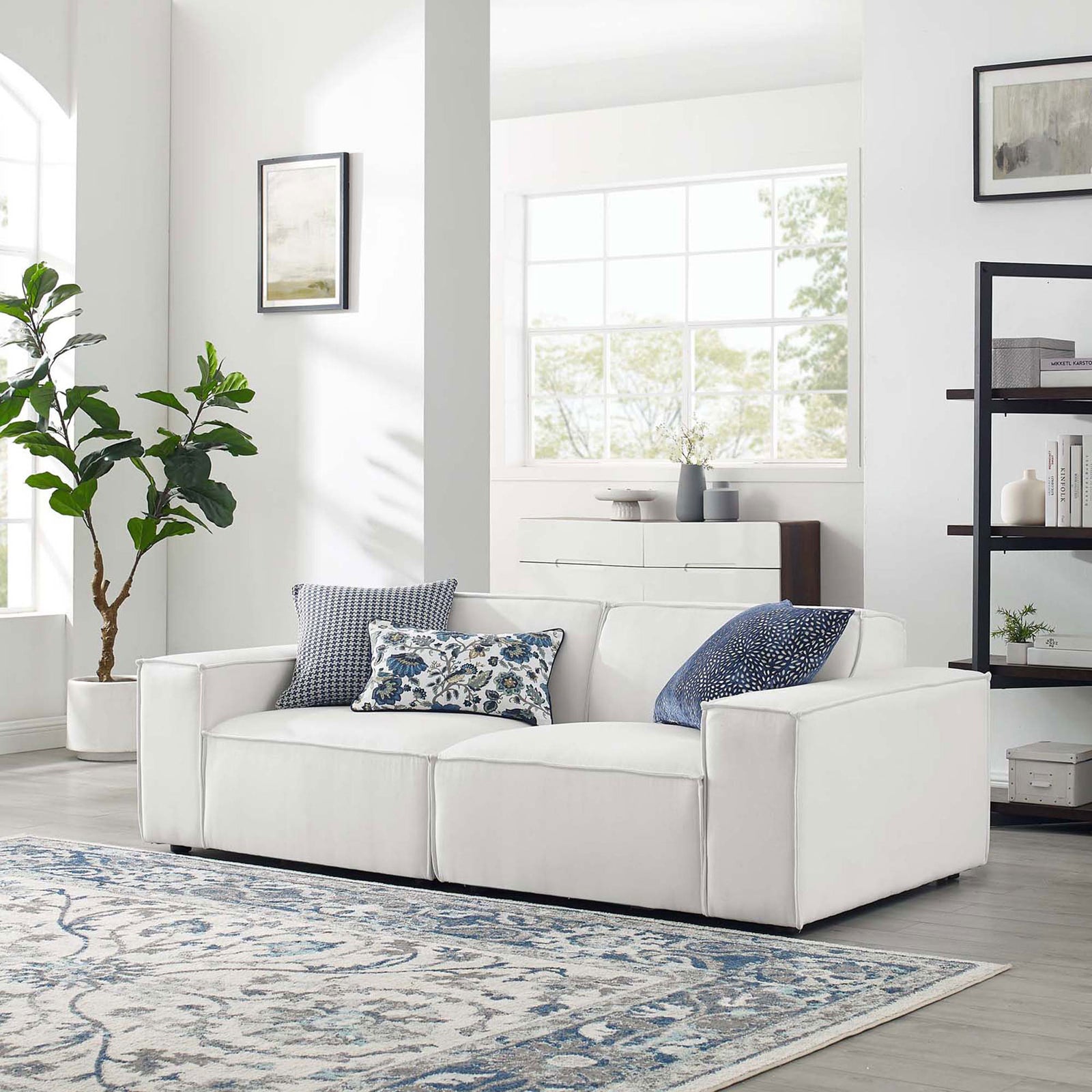 White sectional sofa styled in a bright living room with patterned pillows and area rug || EEI-4111-WHI || front_angle_room