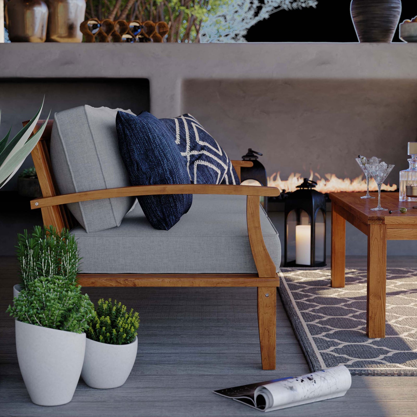 Side of teak outdoor sofa with layered navy pillows beside modern planters and a low table || EEI-4176-NAT-GRY || detail_room