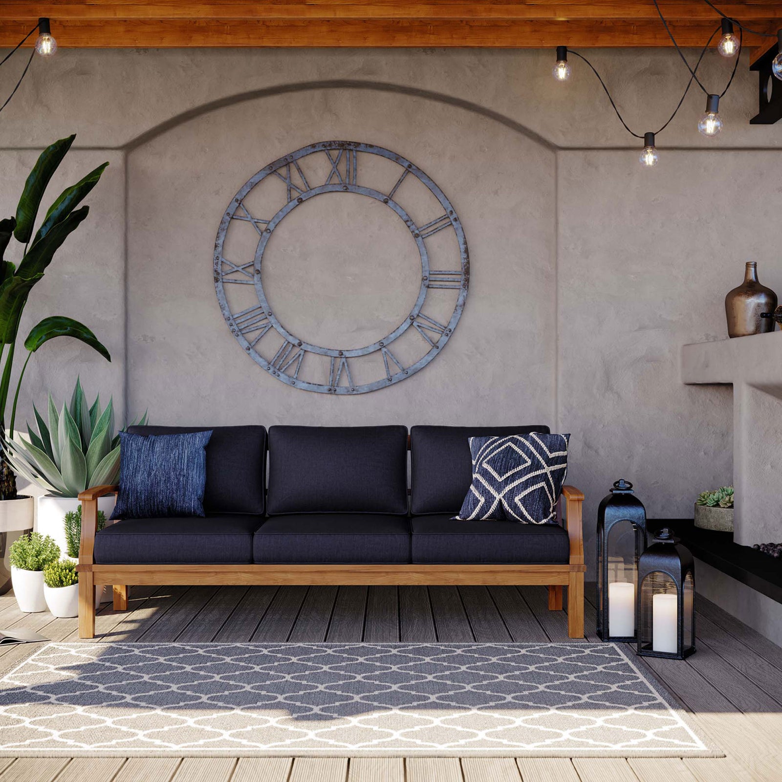 Navy cushioned teak sofa styled on a covered deck with lanterns, rug, and oversized wall clock || EEI-4176-NAT-NAV || front_angle_room