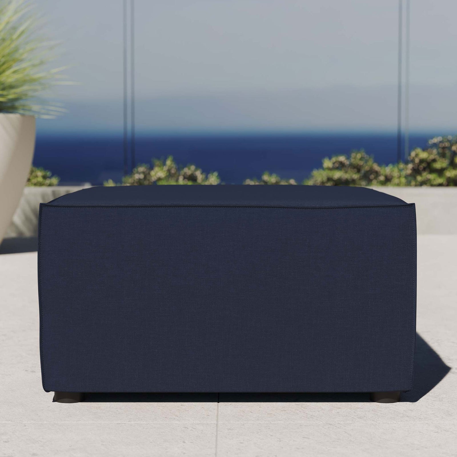 Navy outdoor sectional ottoman styled on a coastal patio with clear sky and greenery || EEI-4211-NAV || front_room
