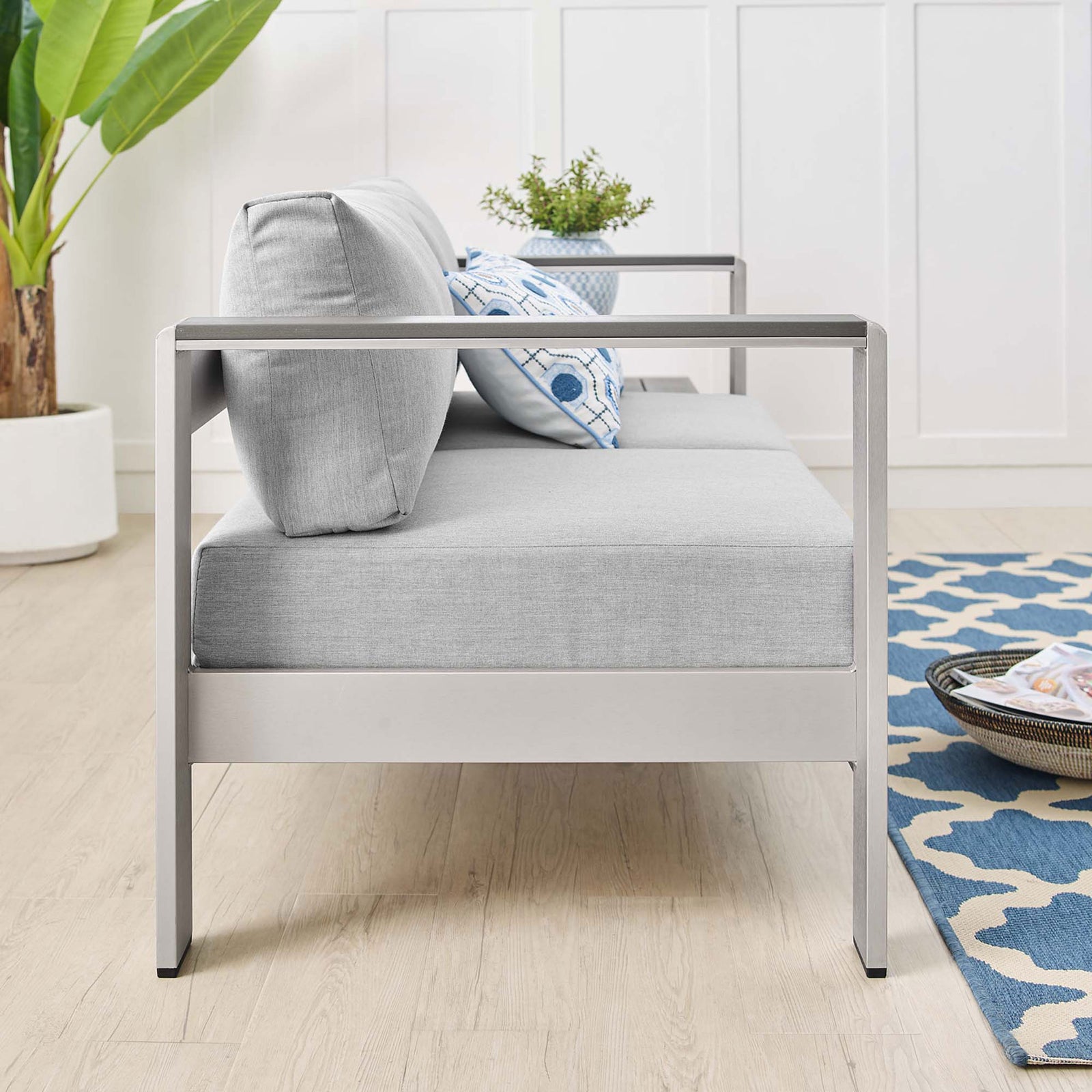 Side view of loveseat in airy room setting with potted plant and patterned blue rug || EEI-4226-SLV-GRY || side_room