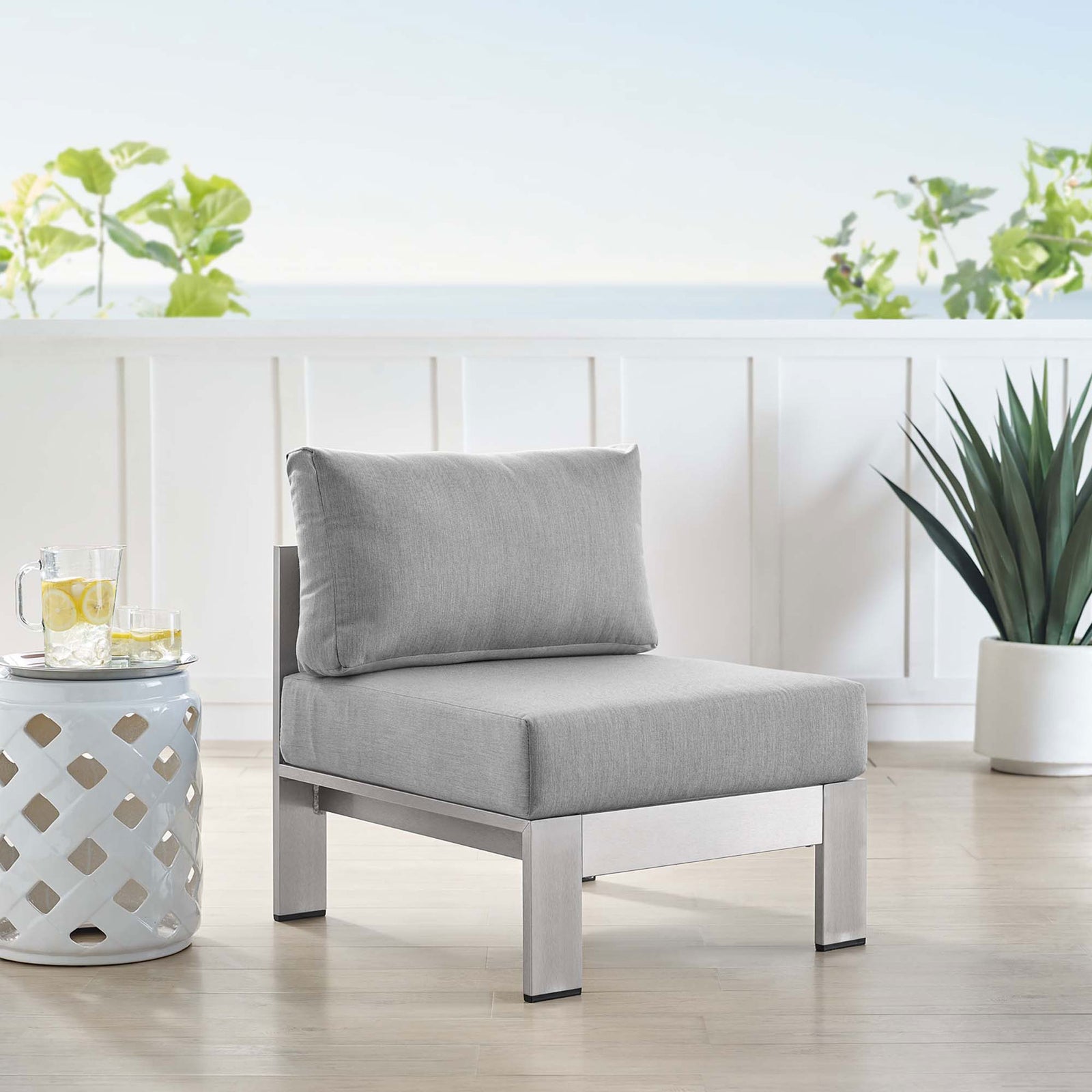 Gray armless Sunbrella(r) chair anchors a light, coastal patio lounge arrangement || EEI-4227-SLV-GRY || front_angle_room