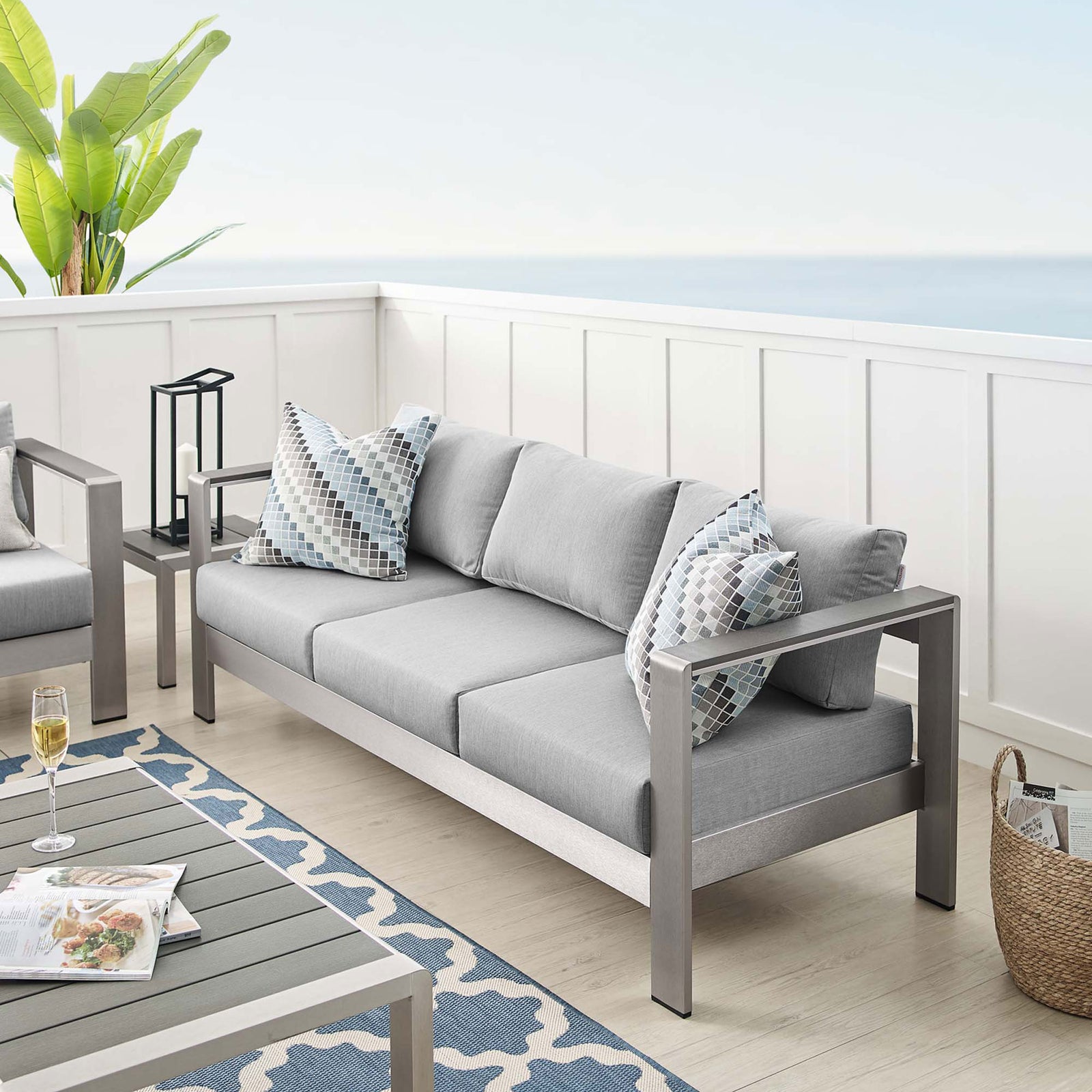 Shore sofa anchors a breezy patio with soft gray cushions and coordinating accent pillows || EEI-4228-SLV-GRY || front_angle_room