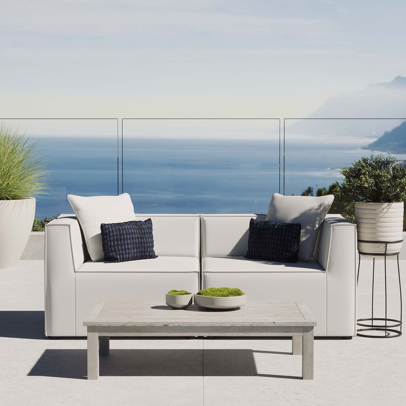 White upholstered patio loveseat creating a relaxed seating area with expansive coastal views. || EEI-4377-WHI || front_room