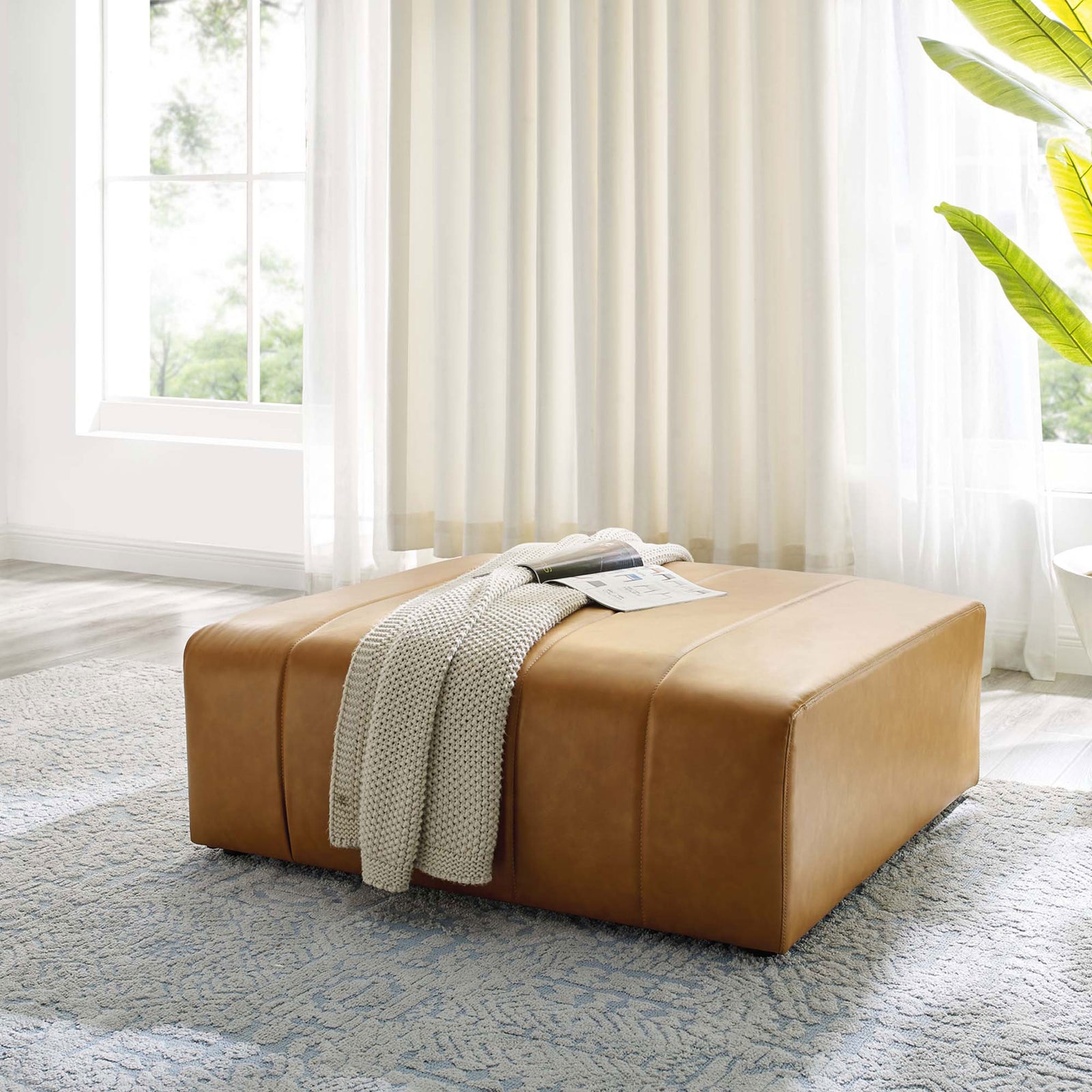 Tan vegan leather ottoman anchors a bright living room, styled with a cozy knit throw and room to rest books or trays || EEI-4401-TAN || front_angle_room