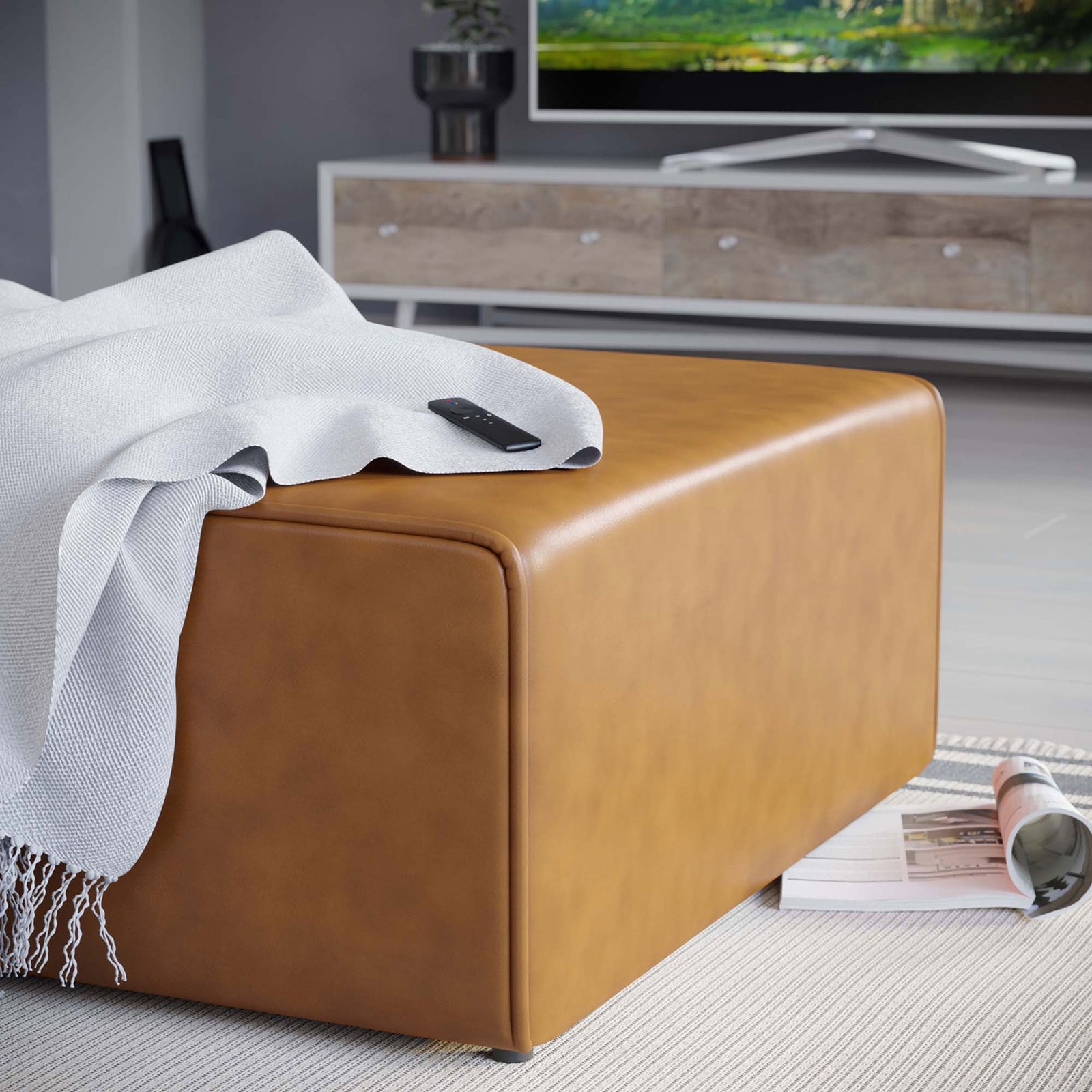 Tan vegan leather ottoman styled with a throw blanket and remote for relaxed lounging in a modern living room || EEI-4624-TAN || detail_room