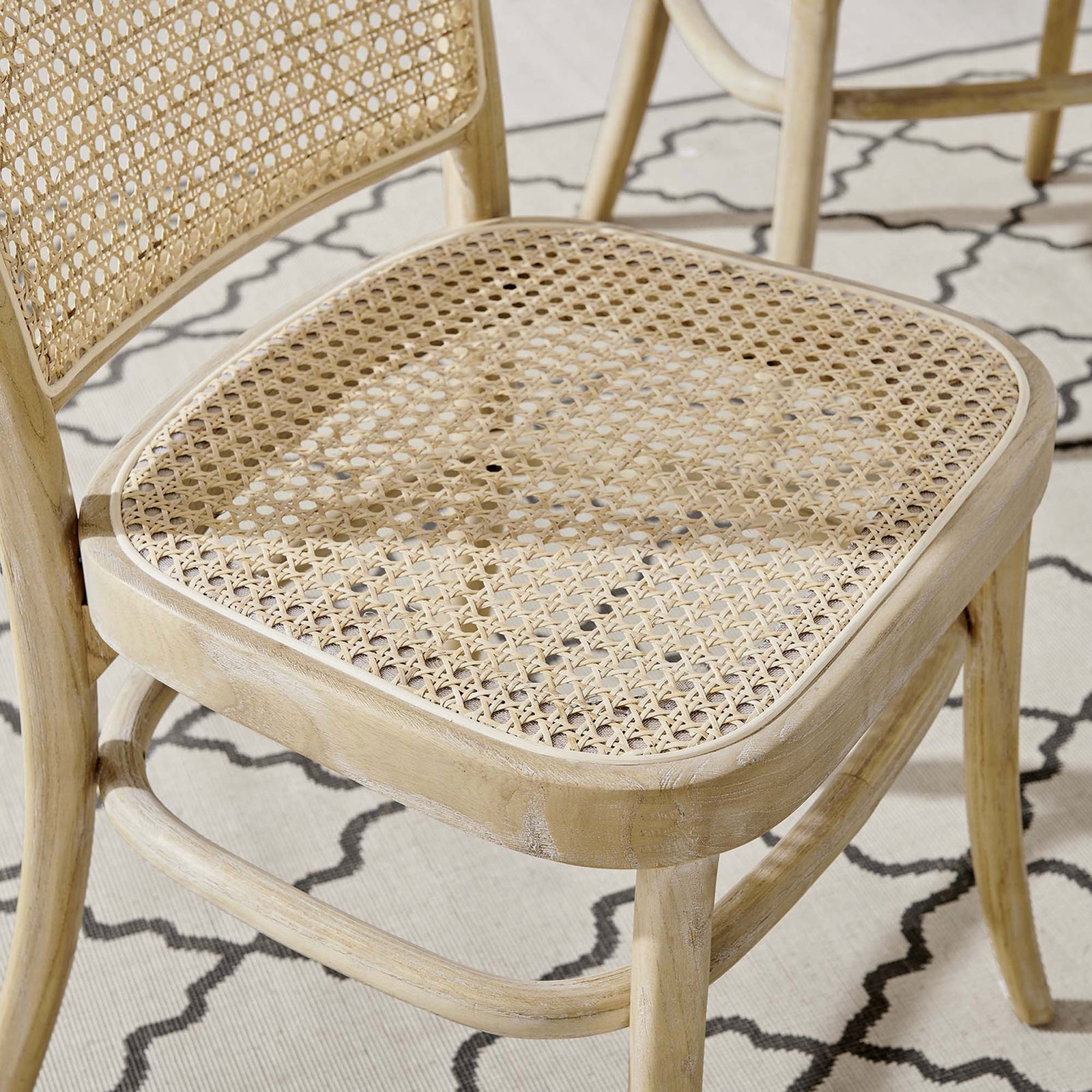 Rattan cane seat over a patterned rug, showing how the chair layers natural texture into your decor. || EEI-4646-GRY || detail_room
