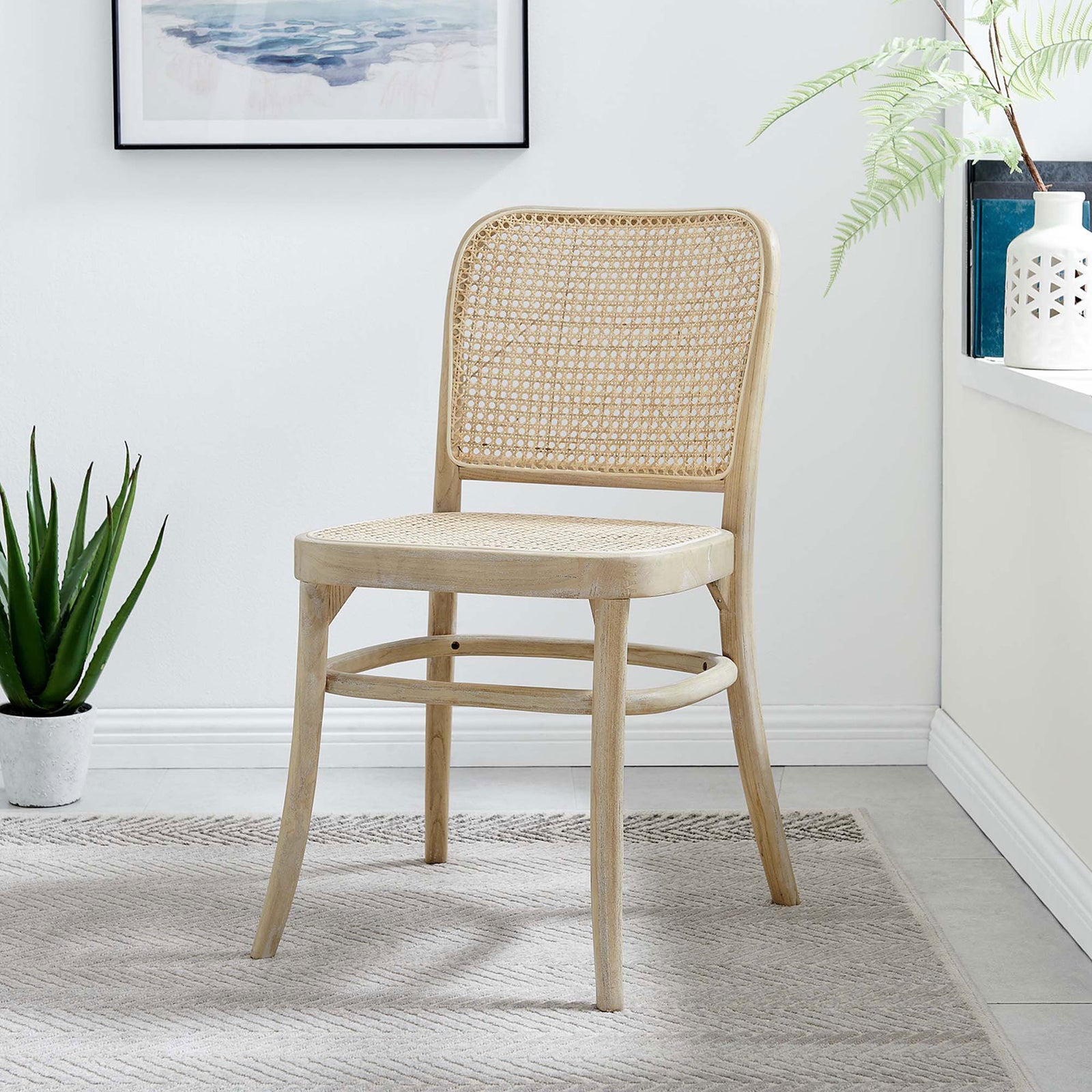 Cane-back dining chair styled in a bright, coastal-inspired room with neutral rug and greenery. || EEI-4646-GRY || front_room