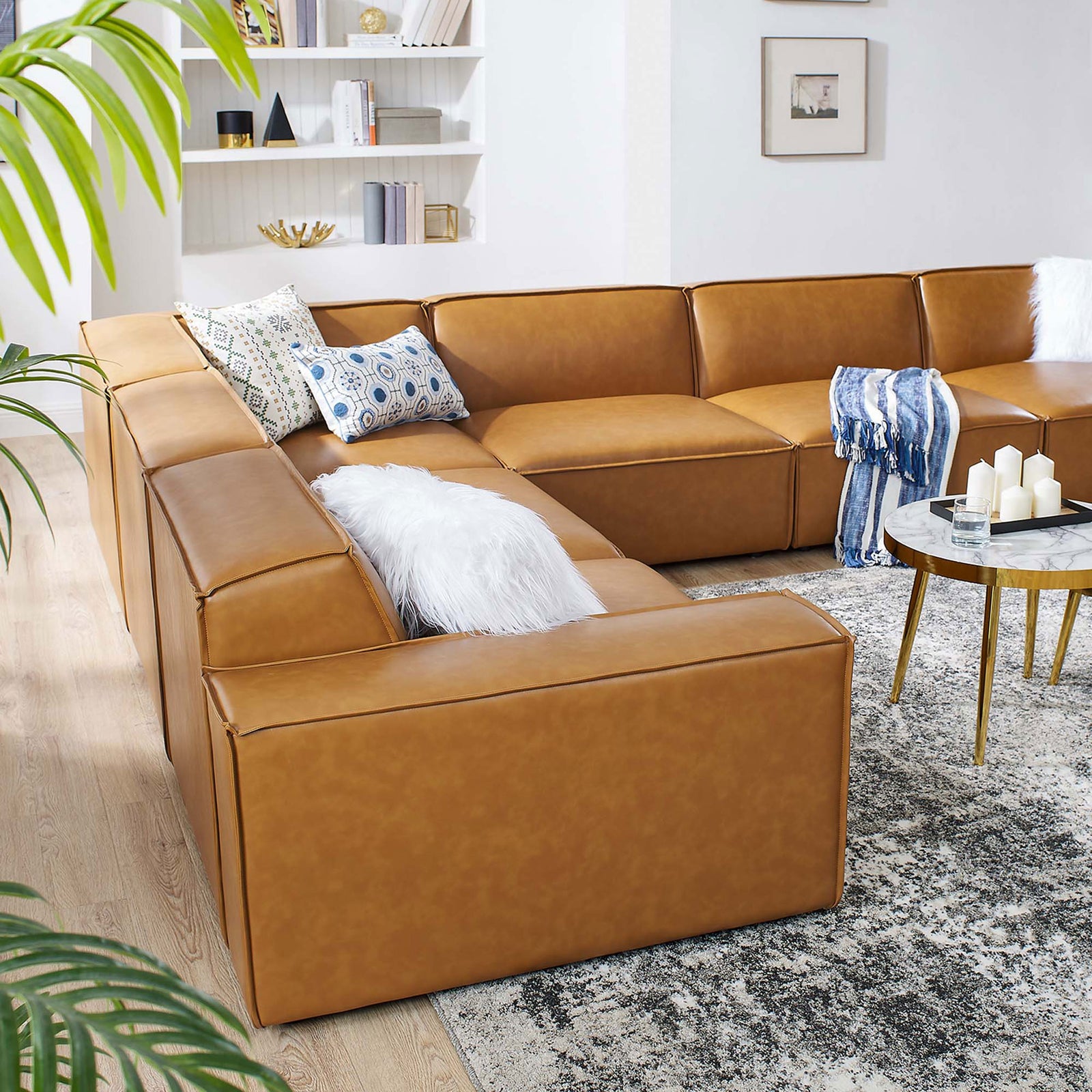 Large tan vegan leather sectional anchoring a modern living room with layered pillows and decor || EEI-4715-TAN || back_angle_room