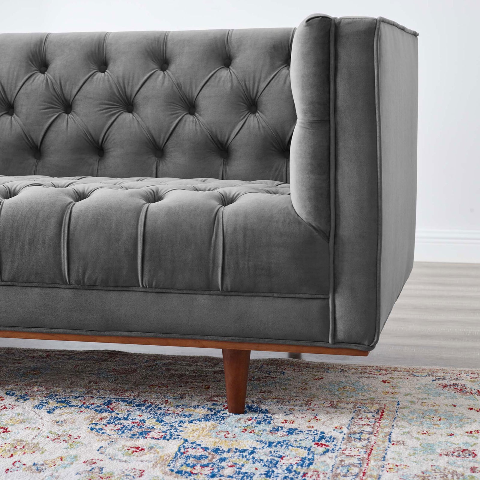 Tufted gray velvet sofa corner showcasing slim tapered wood leg over patterned rug || EEI-4722-GRY || leg_room