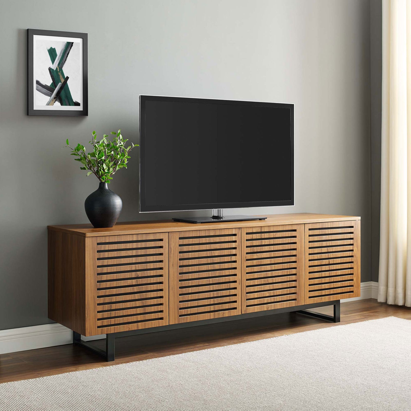 Walnut TV stand with slatted doors and black base styled beneath a large flat-screen TV || EEI-4763-WAL || front_room