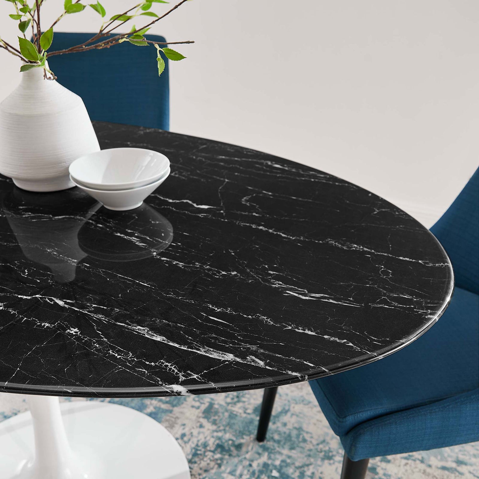 Black faux marble tabletop of the Lippa 60 in. dining table paired with modern blue chairs and white decor || EEI-5186-WHI-BLK || detail_room