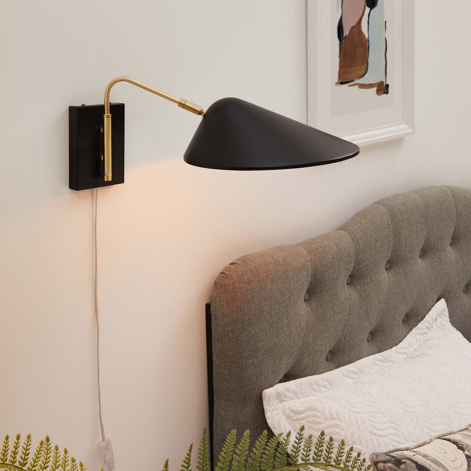Illuminated swing arm sconce casts warm light across the headboard and bedside table. || EEI-5296-BLK || front_angle_on_room