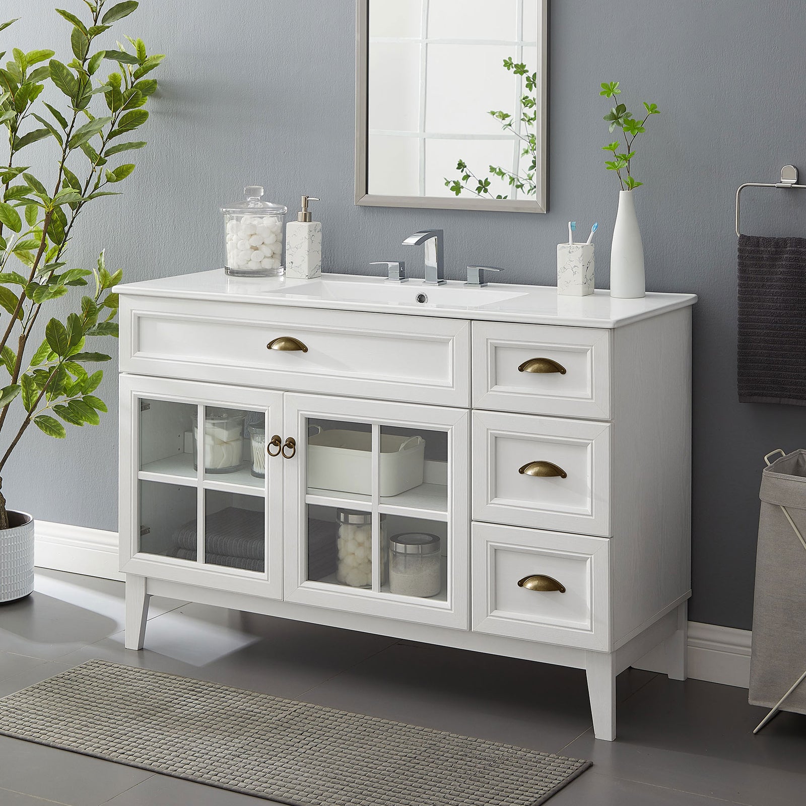 Bright vanity anchors the bath with airy glass doors, brass hardware, and a glossy ceramic basin || EEI-5427-WHI-WHI || front_angle_room