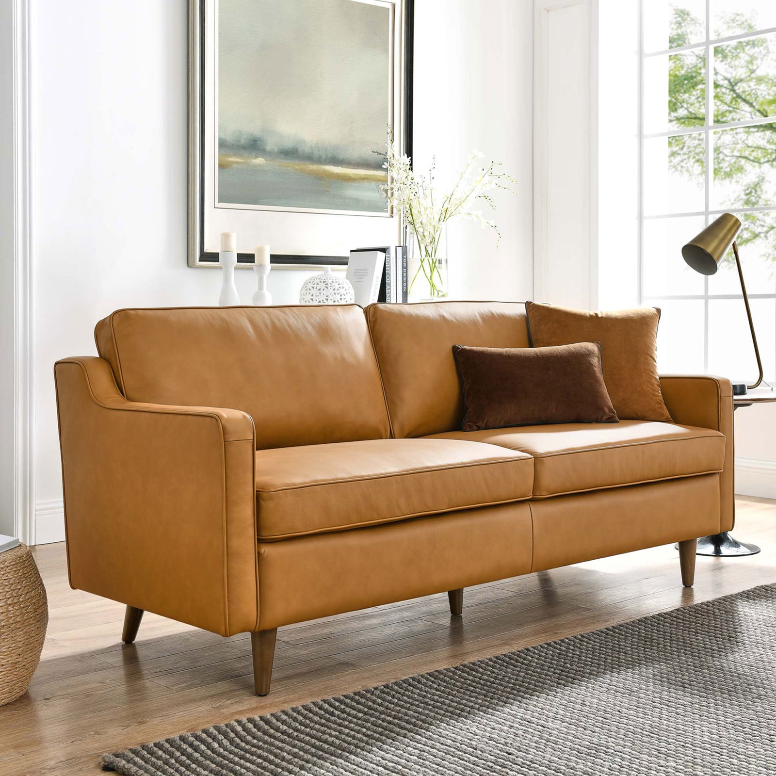 Tan leather sofa styled in a bright living room with accent pillows, rug, and modern decor || EEI-5553-TAN || front_angle_room
