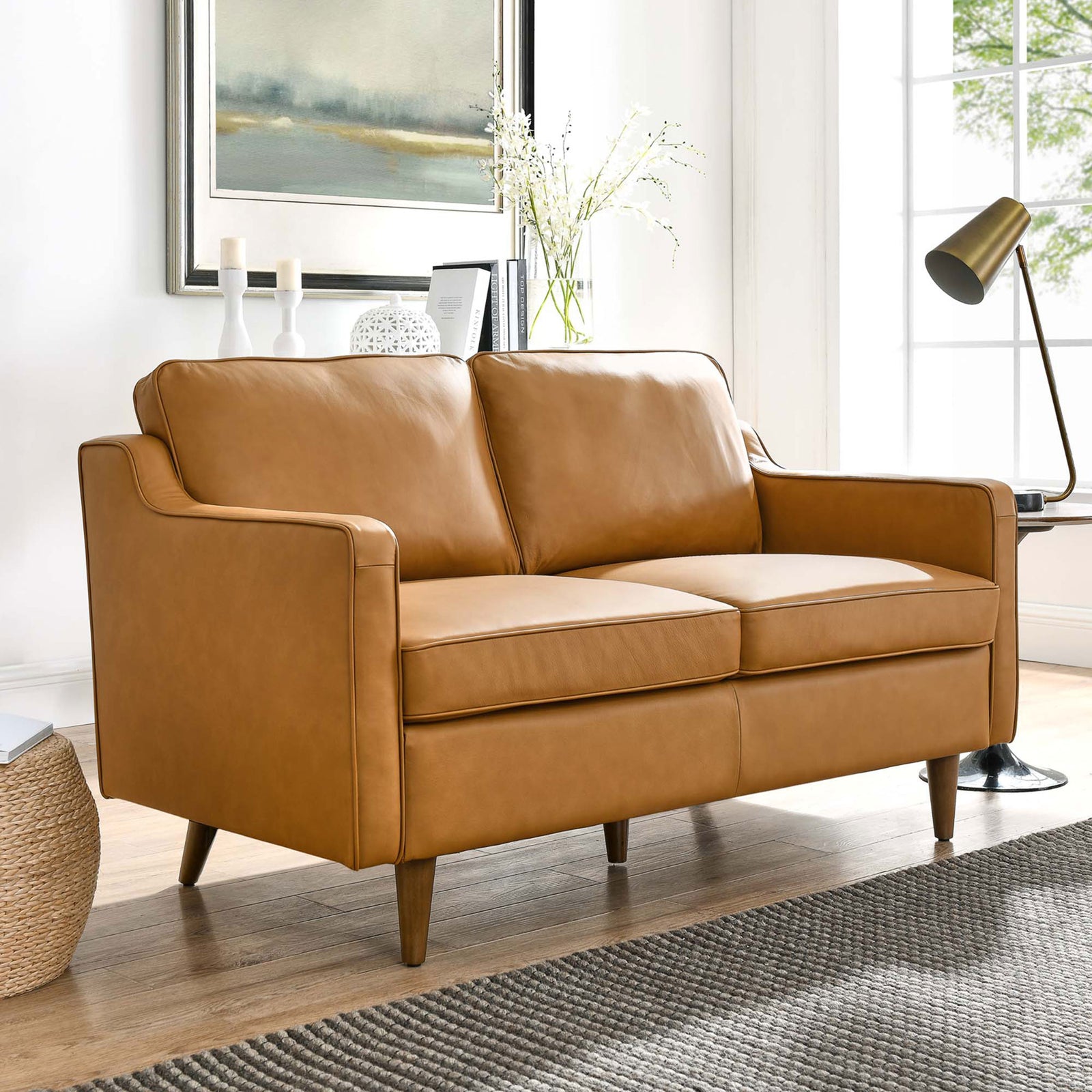 Mid-century tan leather loveseat bringing warm, refined style to a bright living room setting. || EEI-5554-TAN || front_angle_room