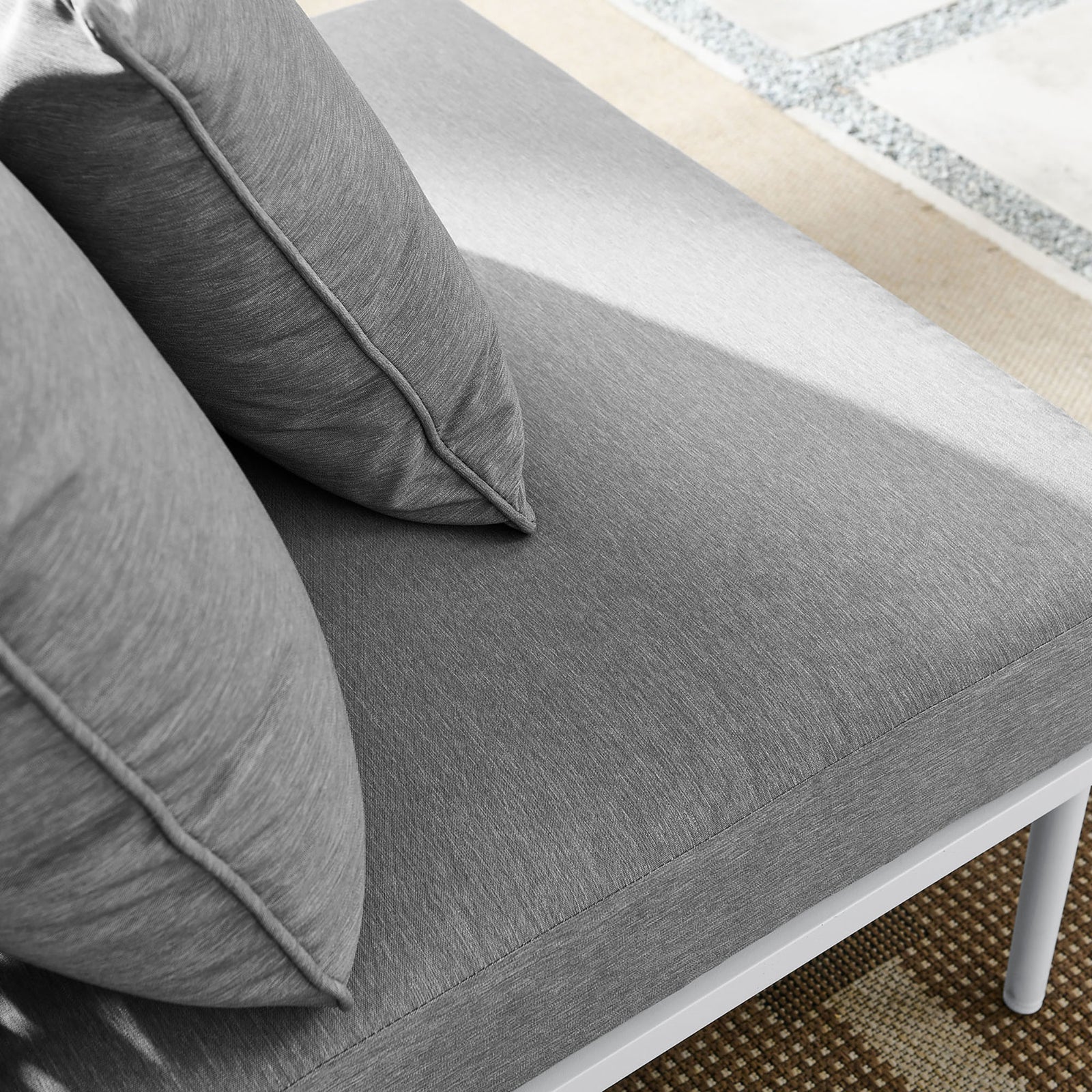 Plush gray cushions of the Stance armless chair resting on a patterned outdoor rug || EEI-5568-WHI-GRY || detail_room