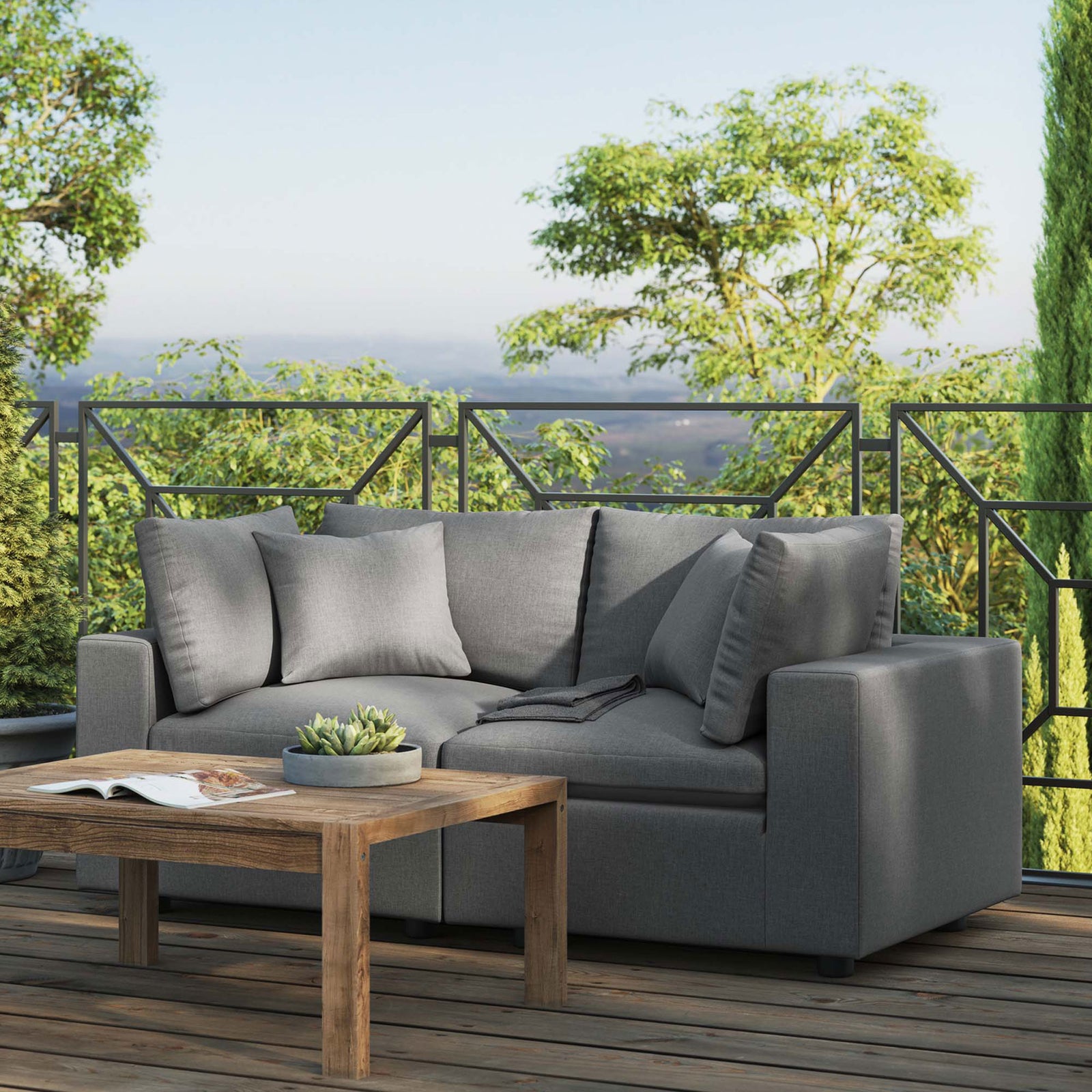 Charcoal outdoor loveseat on a spacious deck with lush greenery and rustic coffee table || EEI-5576-CHA || front_angle_room