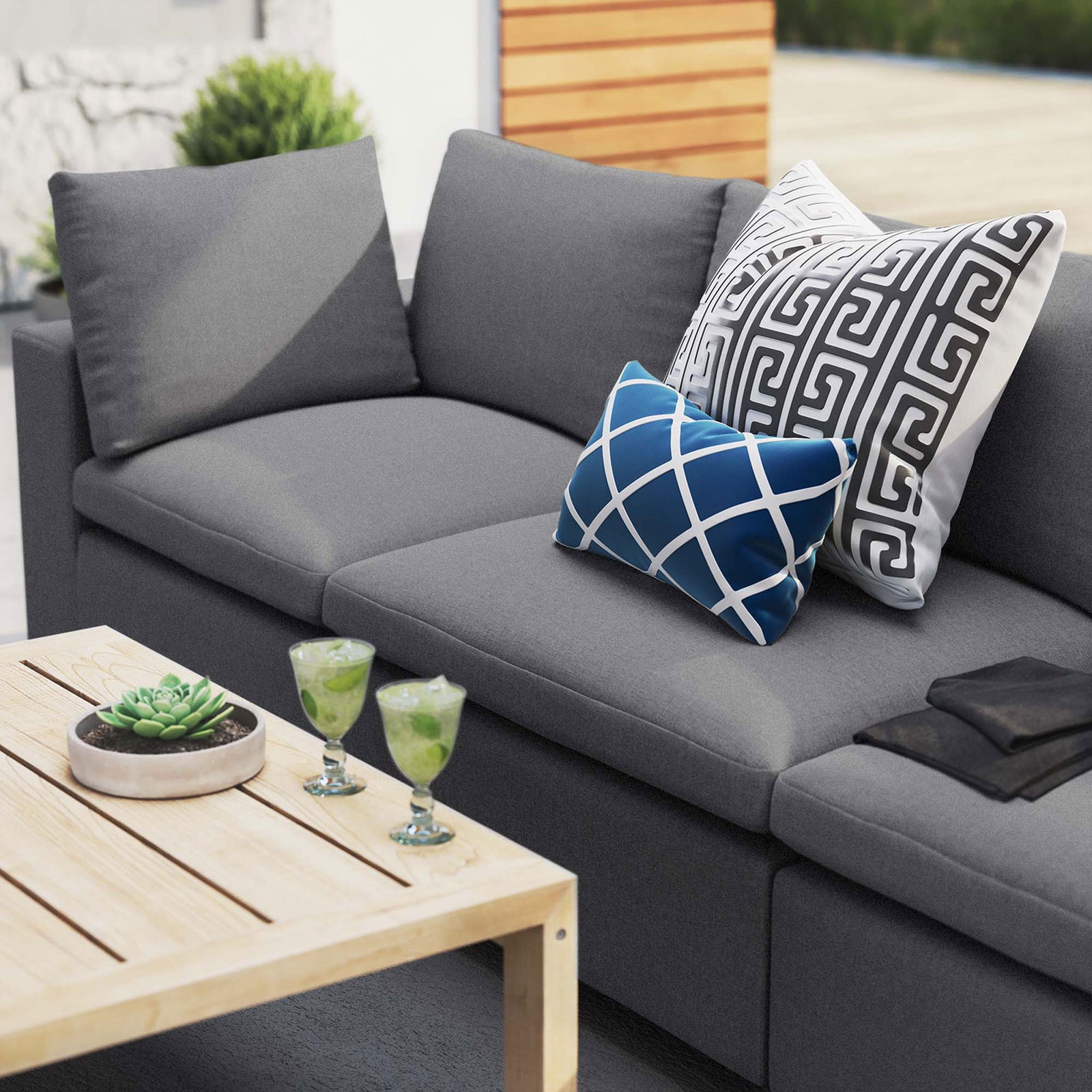 Gray Sunbrella outdoor sofa styled with bold accent pillows, greenery, and a slatted wood coffee table || EEI-5579-SLA || detail_room
