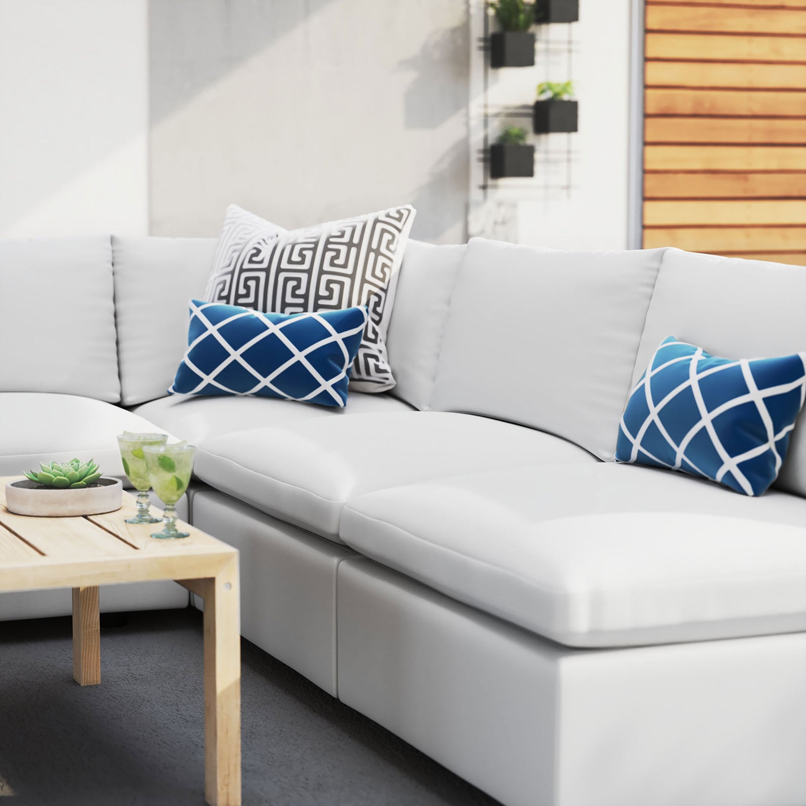 White Sunbrella outdoor sectional styled with graphic blue pillows on a bright, modern patio. || EEI-5588-WHI || detail_room