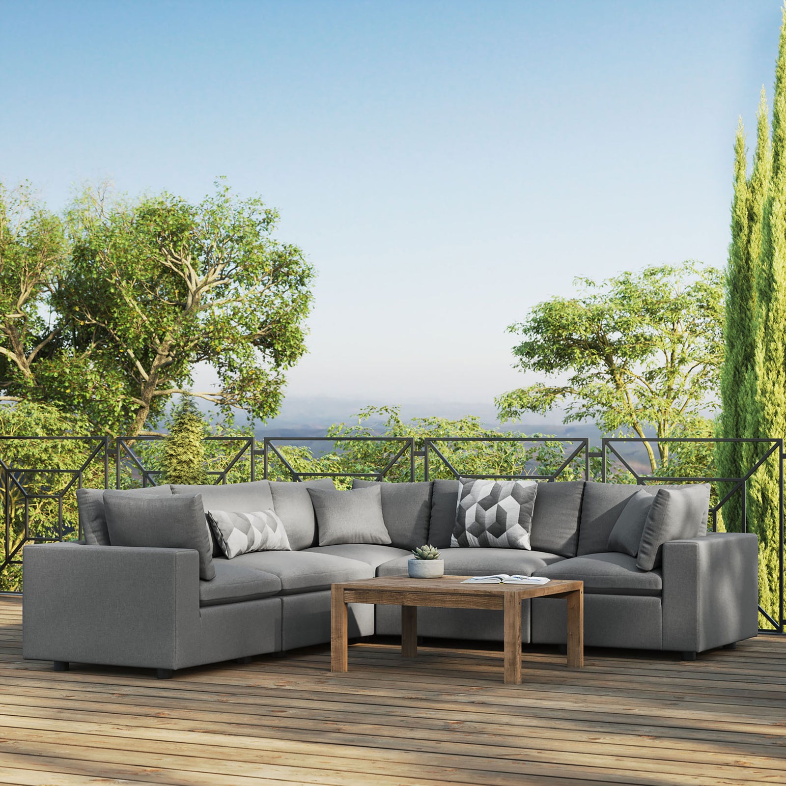Charcoal Commix outdoor sectional anchoring a spacious deck, paired with a wood coffee table and lush greenery backdrop. || EEI-5589-CHA || front_angle_room