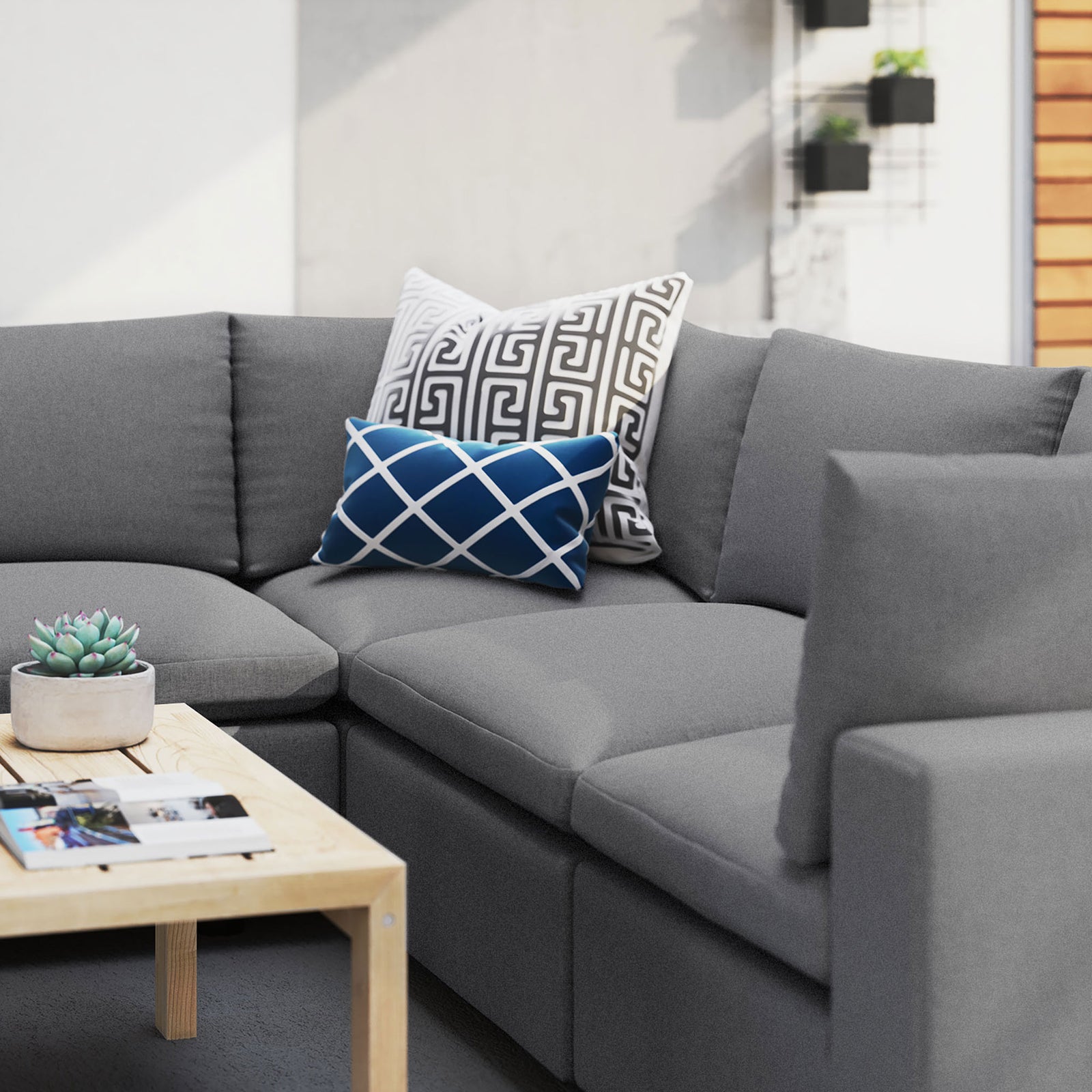 Gray Commix Sunbrella sectional styled with bold accent pillows and a wood table in a modern outdoor space. || EEI-5590-SLA || detail_room