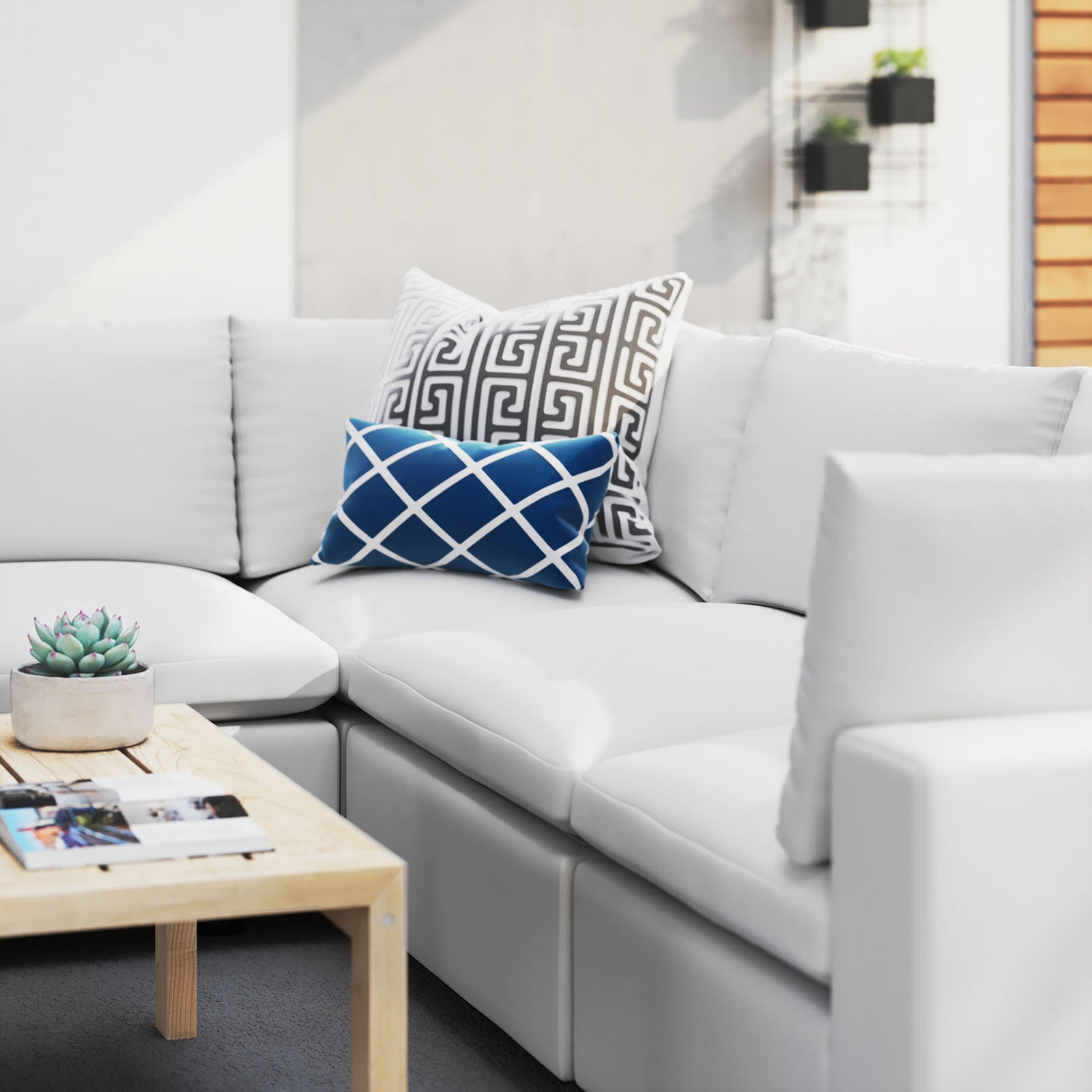 White Commix Sunbrella sectional dressed with patterned accent pillows and a natural wood coffee table outside. || EEI-5590-WHI || detail_room