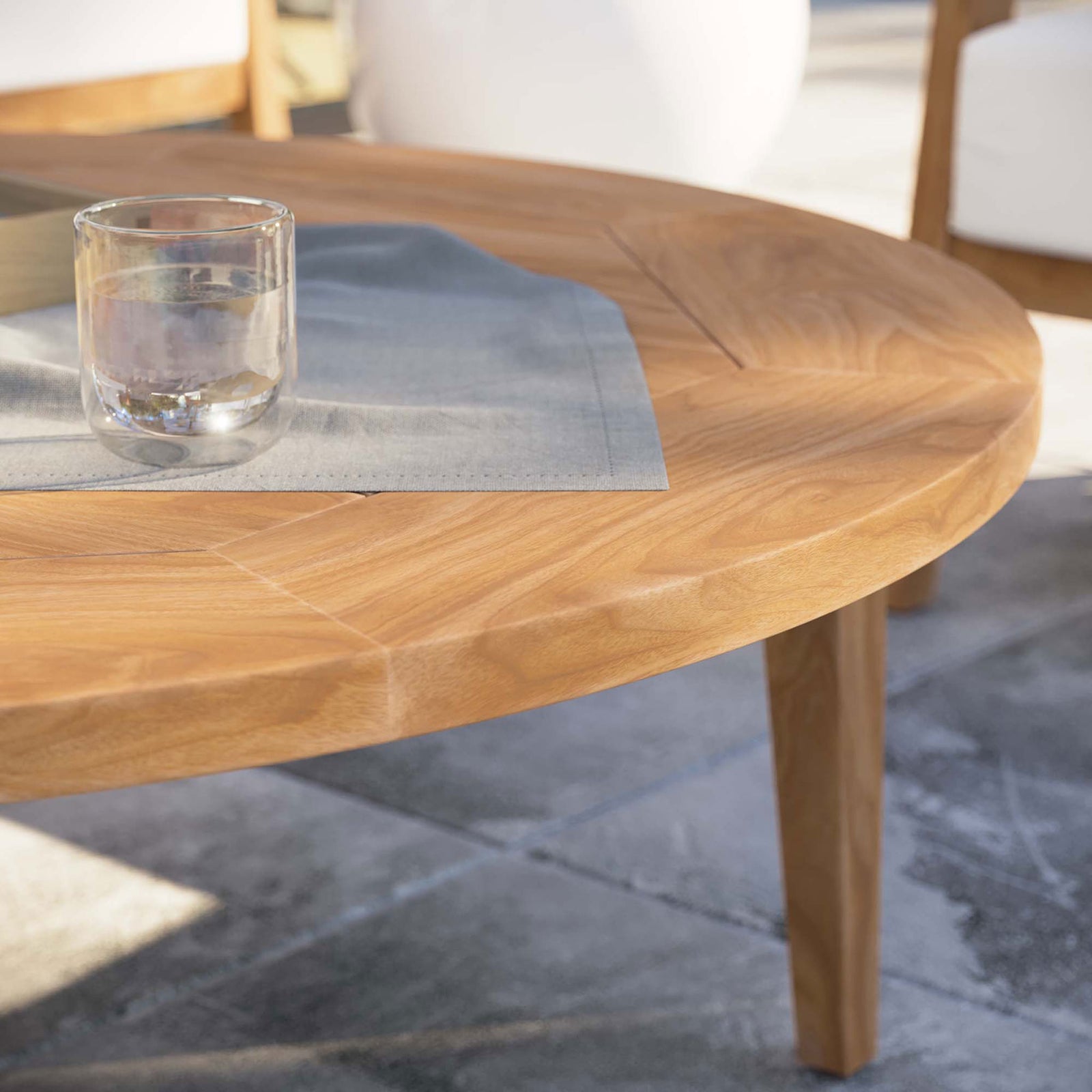 Natural teak coffee table styled with glassware on a modern stone patio || EEI-5603-NAT || detail_room