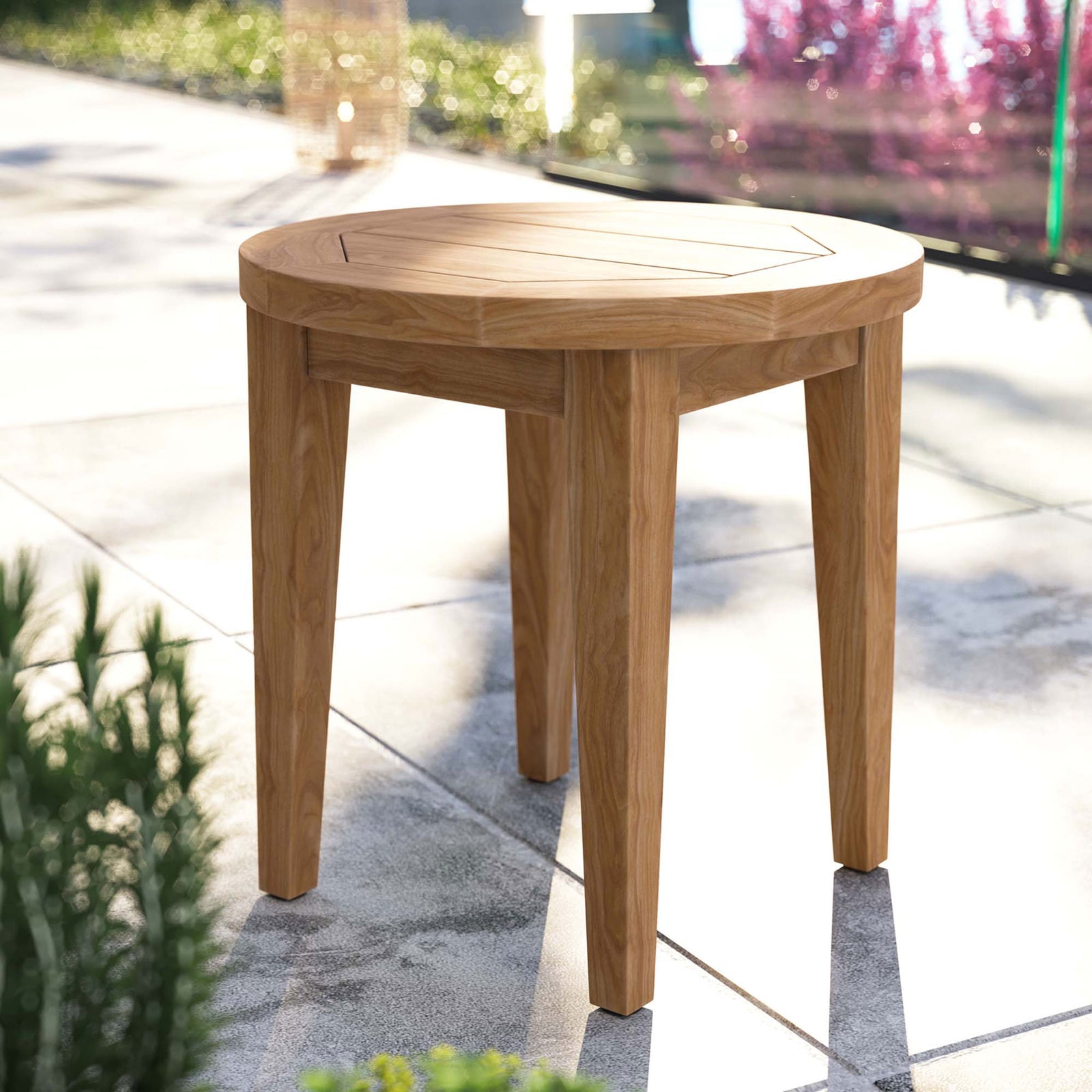 Natural teak outdoor side table styled on a modern patio among lush greenery and stone pavers || EEI-5604-NAT || front_angle_room