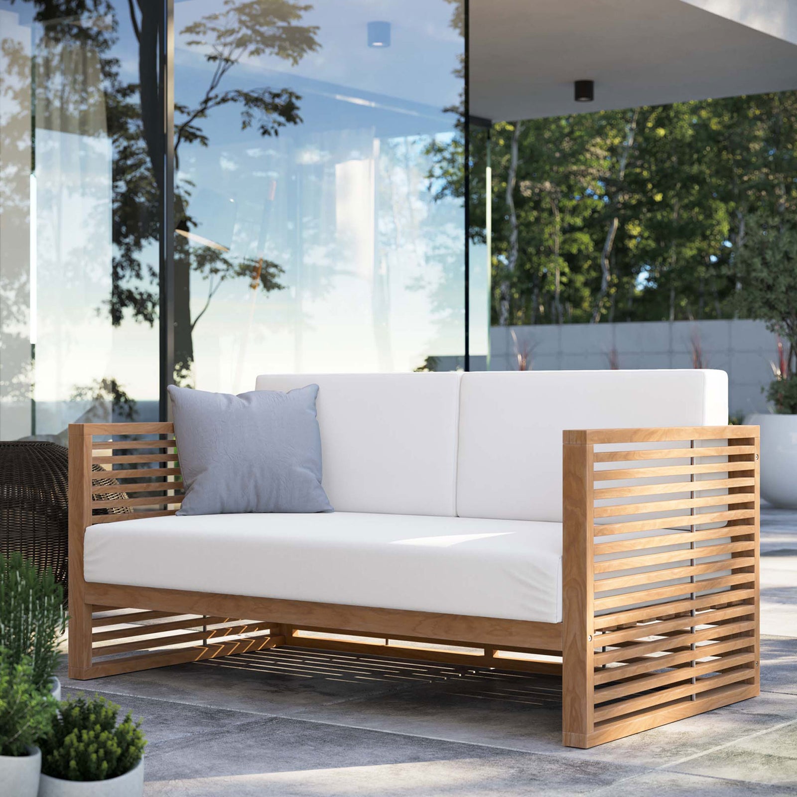 Carlsbad teak outdoor loveseat with white cushions styled on a contemporary patio with garden views. || EEI-5605-NAT-WHI || front_angle_room