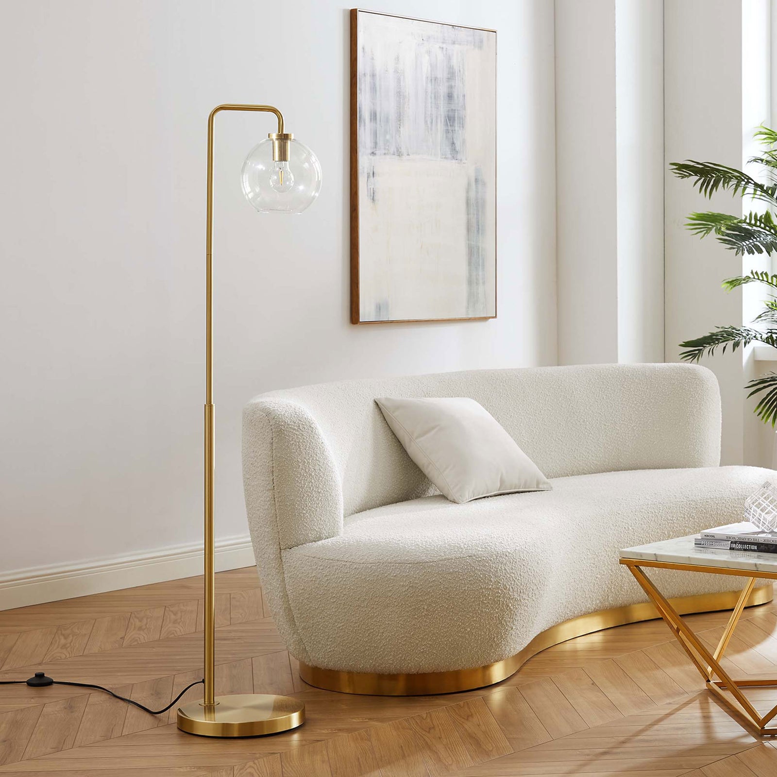 Satin brass glass globe floor lamp beside curved cream sofa and gold-accent coffee table || EEI-5616-SBR || front_angle_room