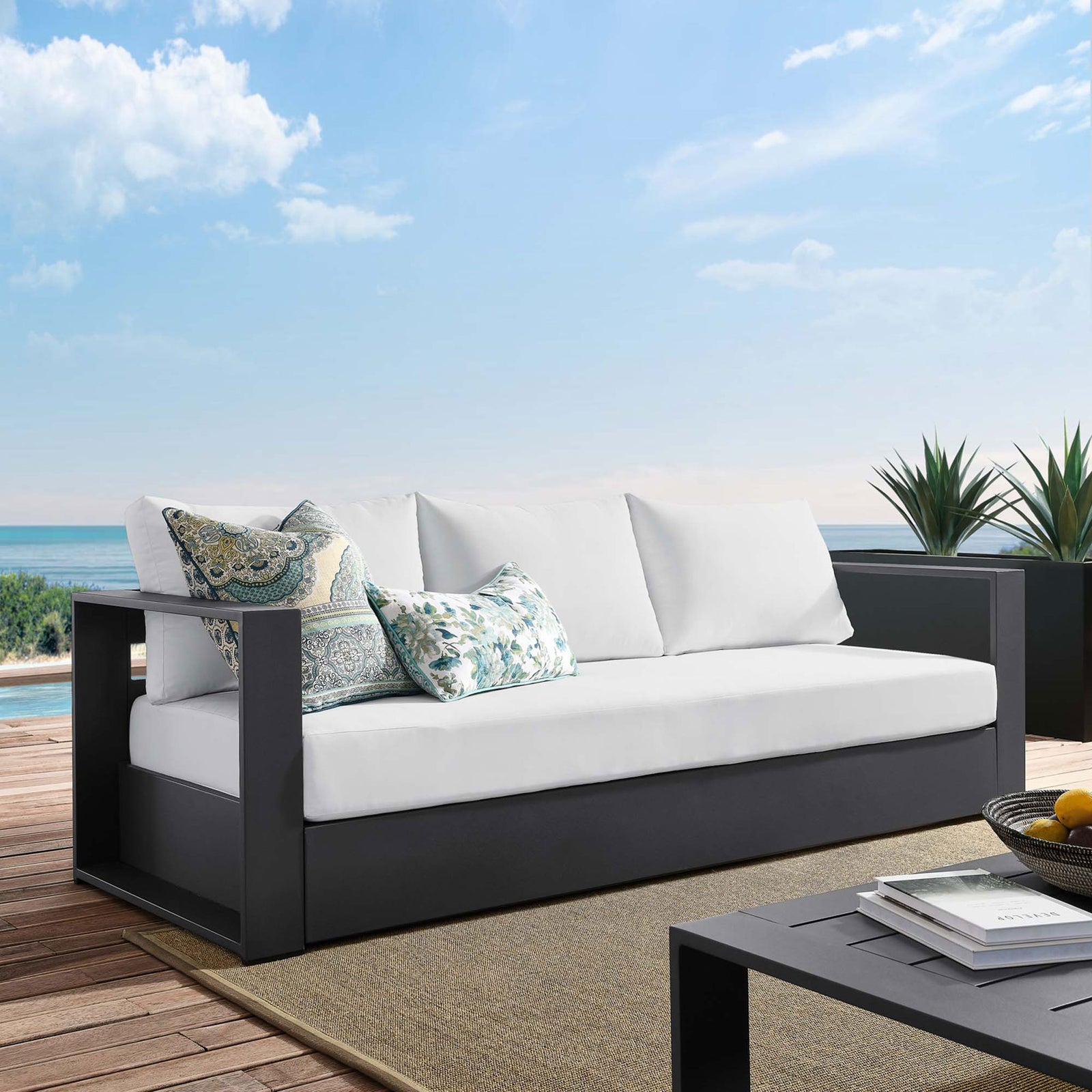 Tahoe outdoor sofa with charcoal frame and white cushions styled on a breezy coastal deck. || EEI-5676-GRY-WHI || front_angle_room