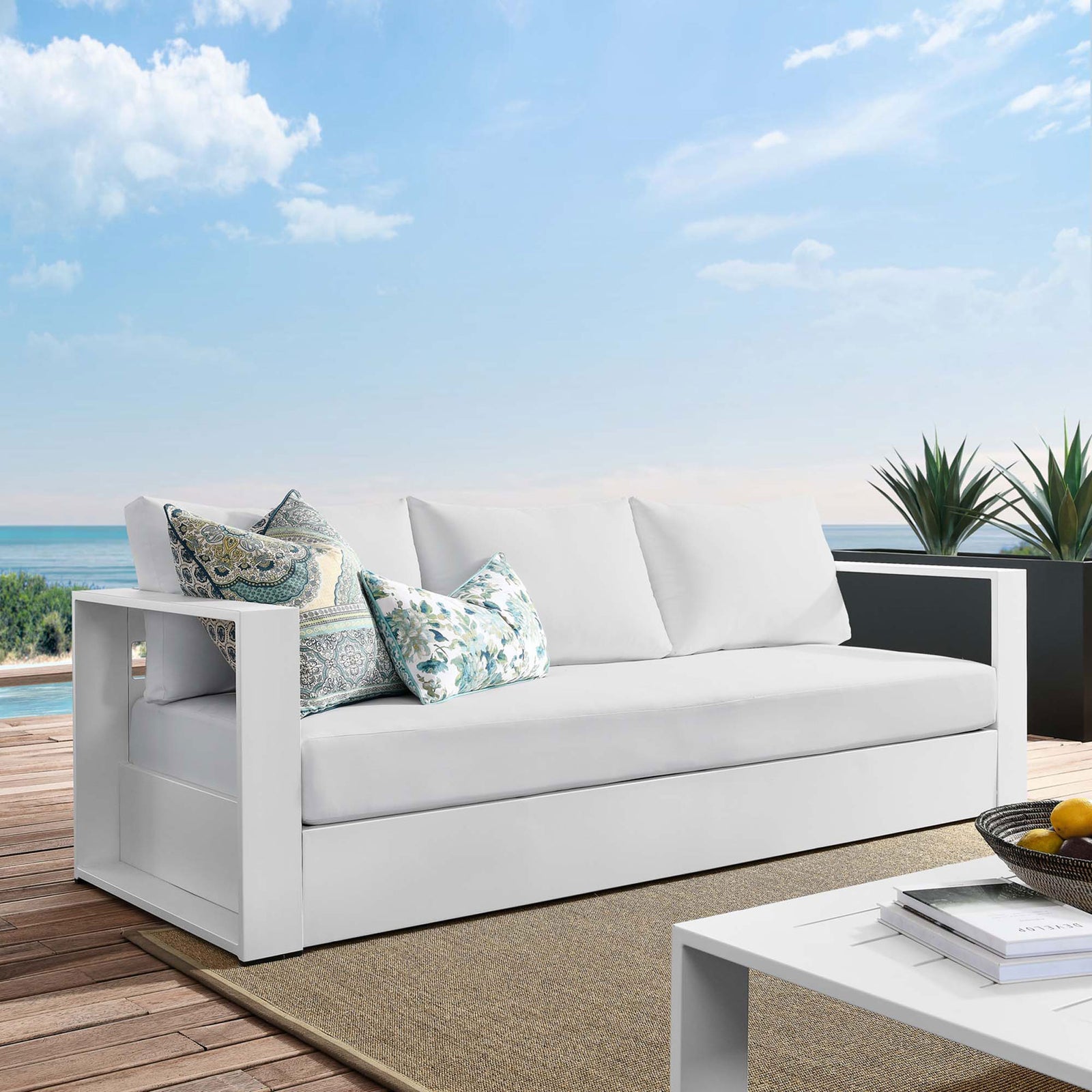 Tahoe outdoor sofa in all white styled on a coastal deck with patterned accent pillows. || EEI-5676-WHI-WHI || front_angle_room