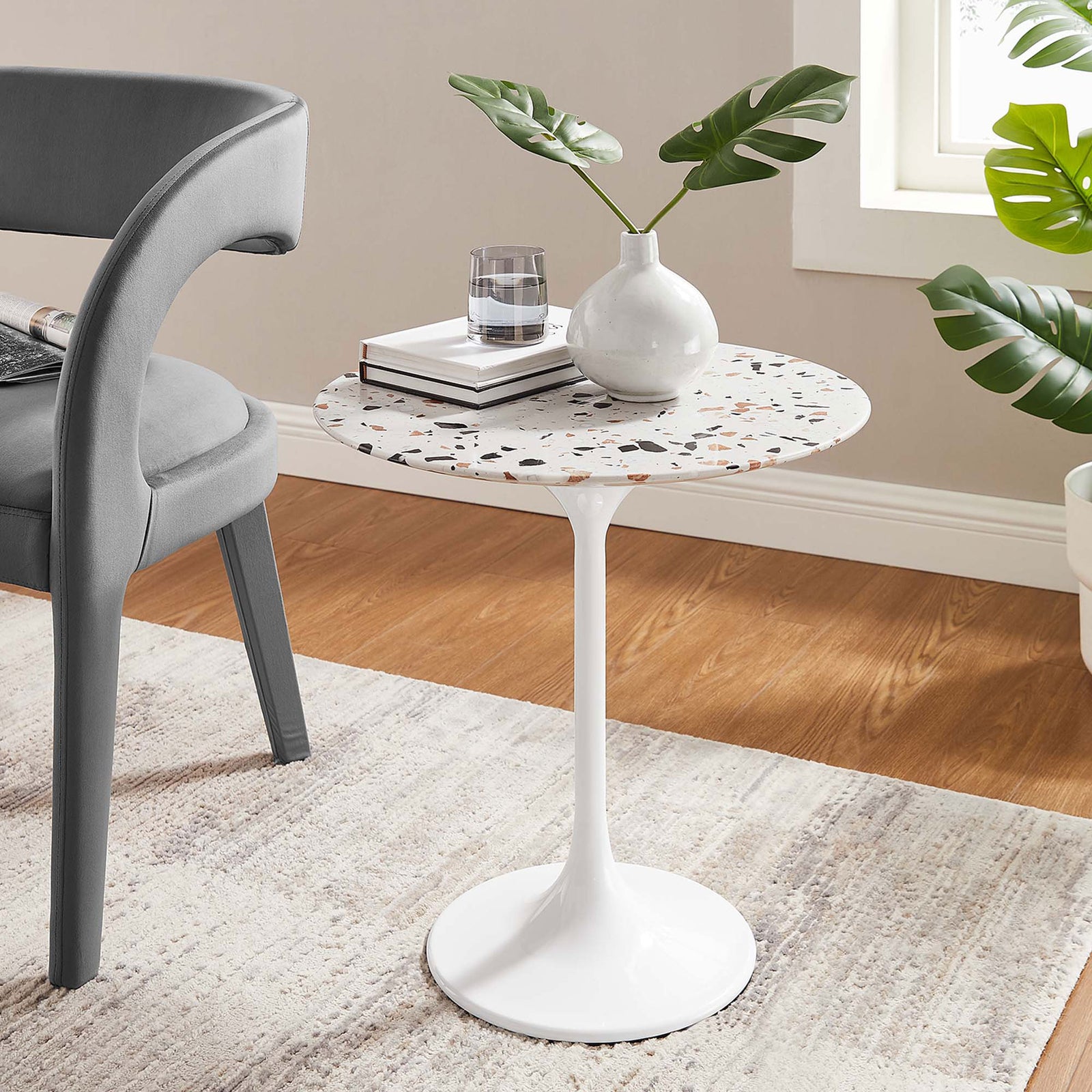 White terrazzo side table beside a gray chair on a light rug in a bright wood-floor living room || EEI-5682-WHI-TER || front_angle_room