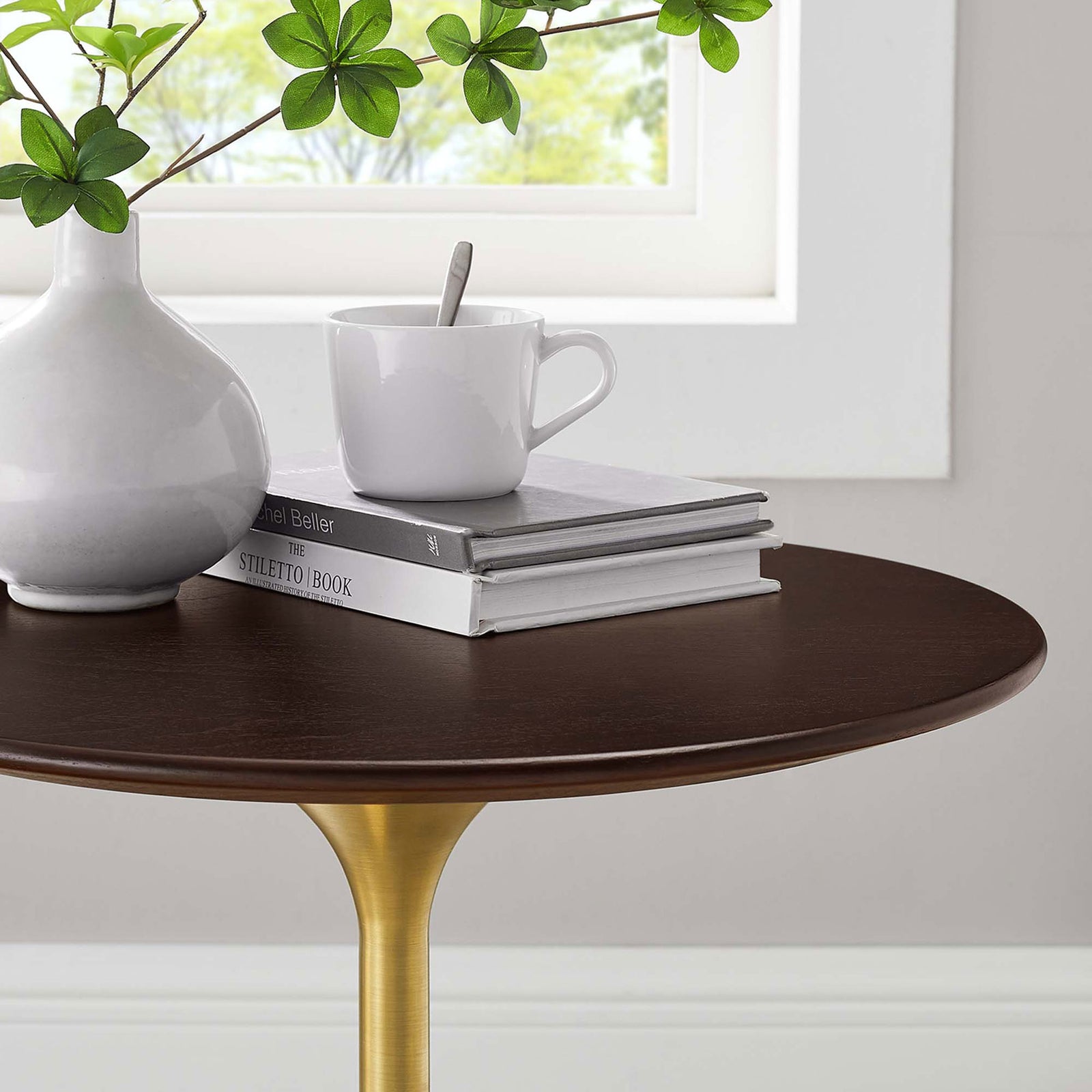 Styled tabletop close up with vase, coffee cup, and books on the warm wood grain surface || EEI-5684-GLD-CHE || detail_room