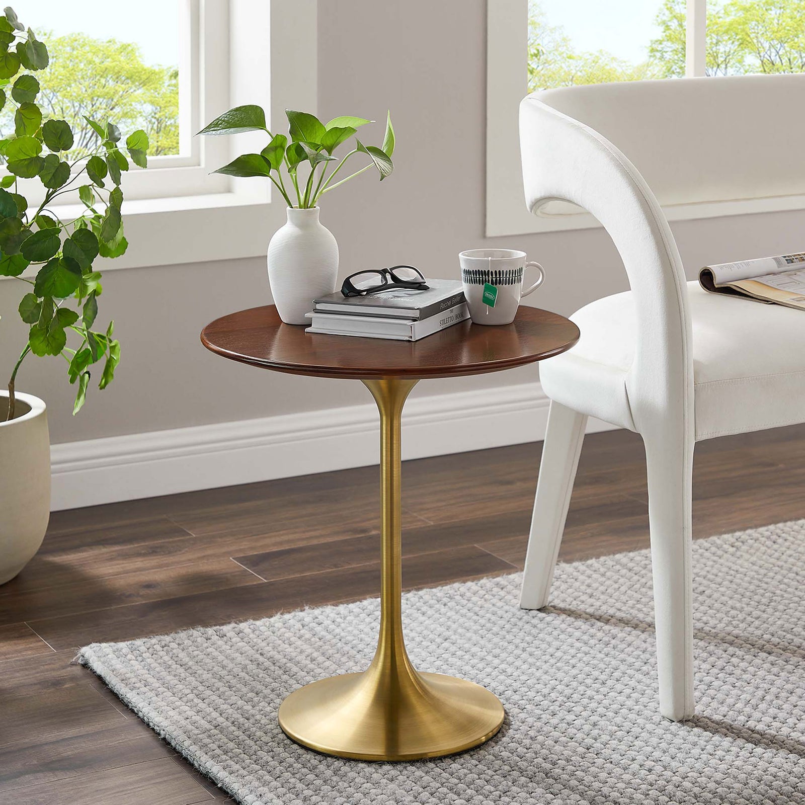 Walnut and gold round side table styled beside a white chair in a bright modern living room || EEI-5684-GLD-WAL || front_angle_room