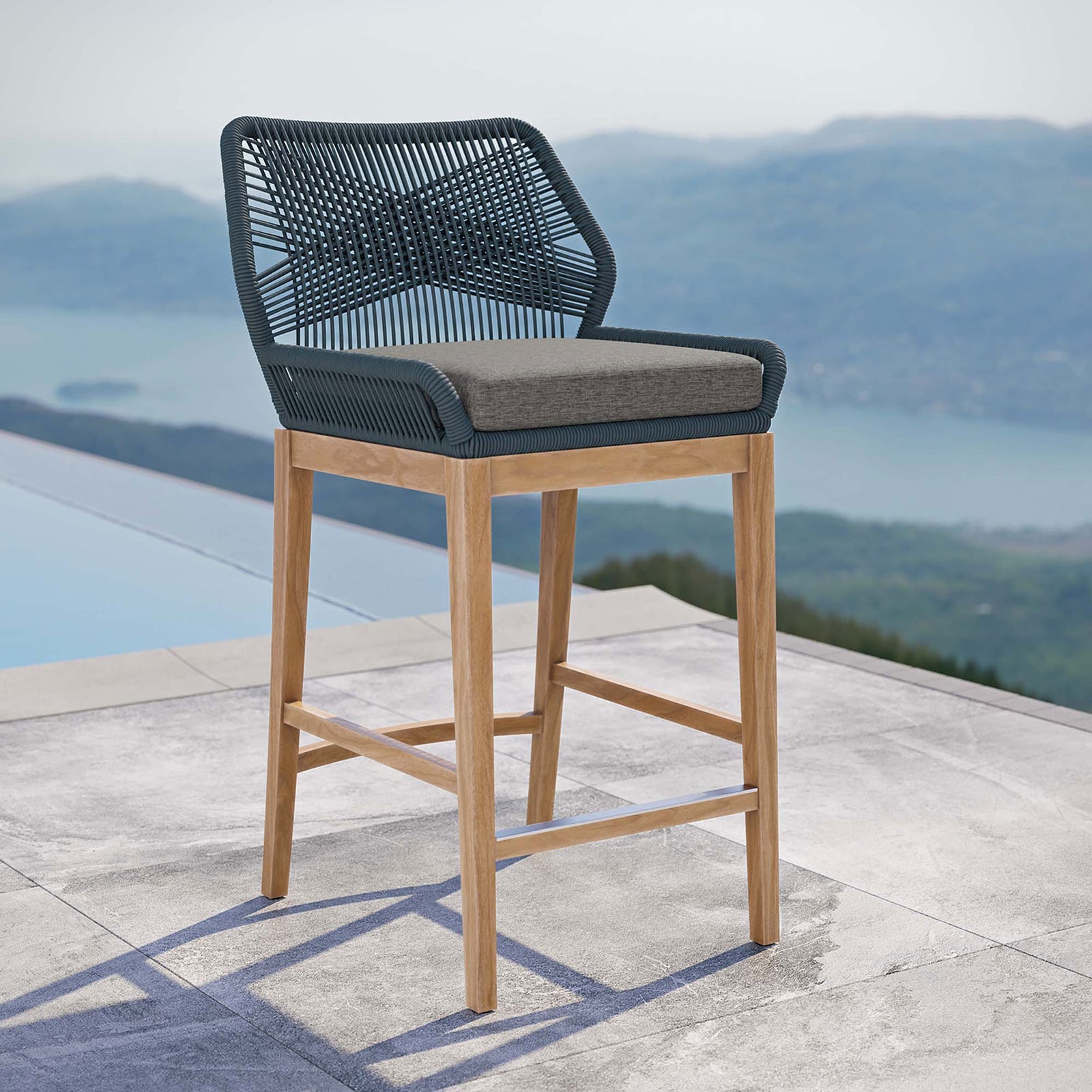Blue graphite rope bar stool with gray cushion and teak base styled on a modern poolside patio. || EEI-5746-BLU-GPH || front_angle_room