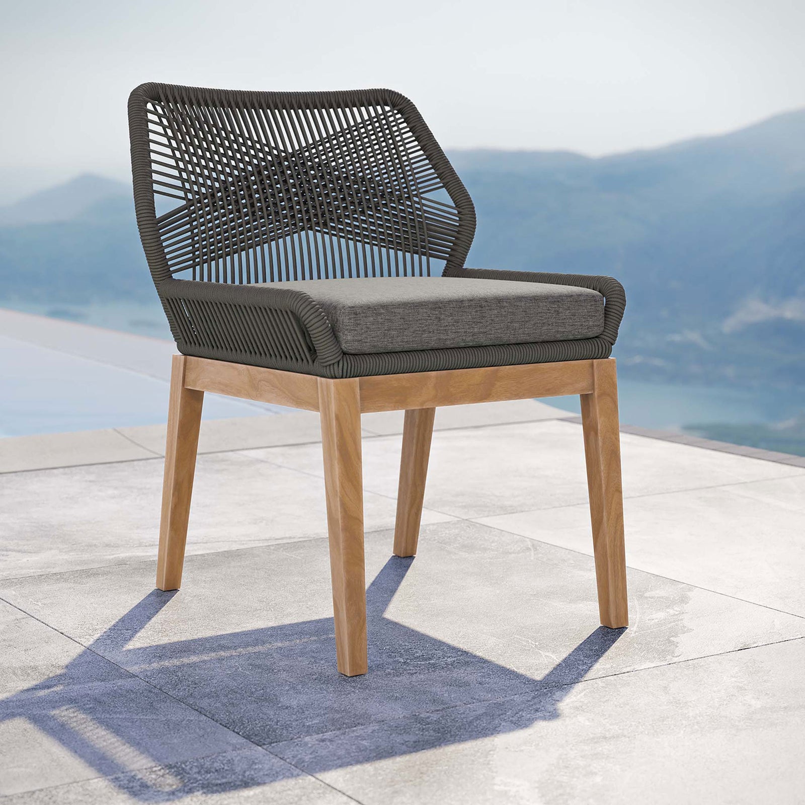 Gray graphite rope dining chair with gray cushion arranged by an infinity pool for contemporary outdoor dining || EEI-5747-GRY-GPH || front_angle_room