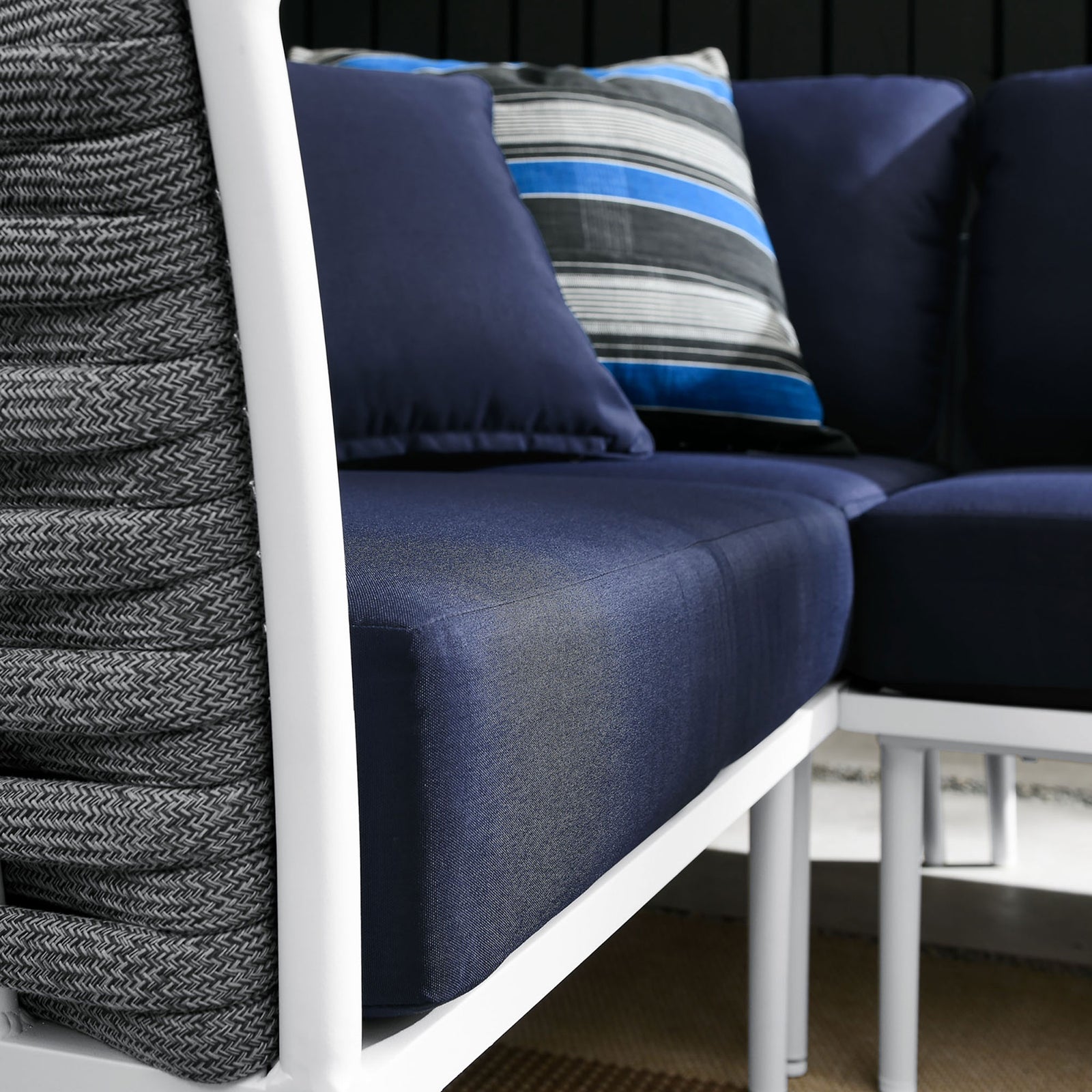 Styled patio vignette spotlights navy cushions, patterned accent pillows, and woven textures around the sectional. || EEI-5753-WHI-NAV || detail_room