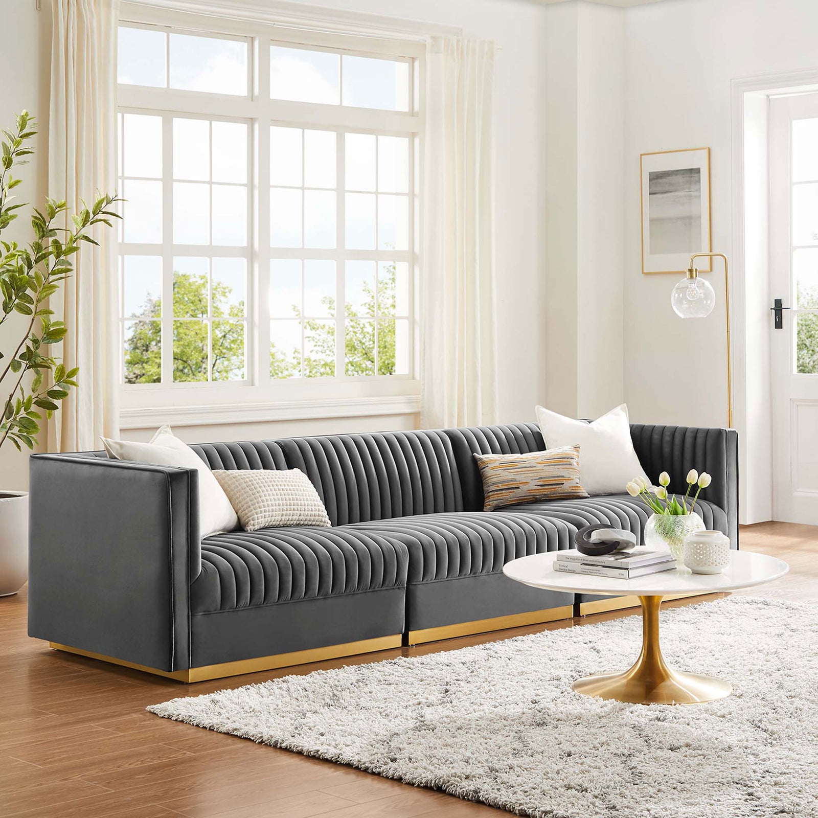 Gray channel tufted modular sofa styled in a bright living room with a round white and gold coffee table || EEI-5825-GRY || front_room