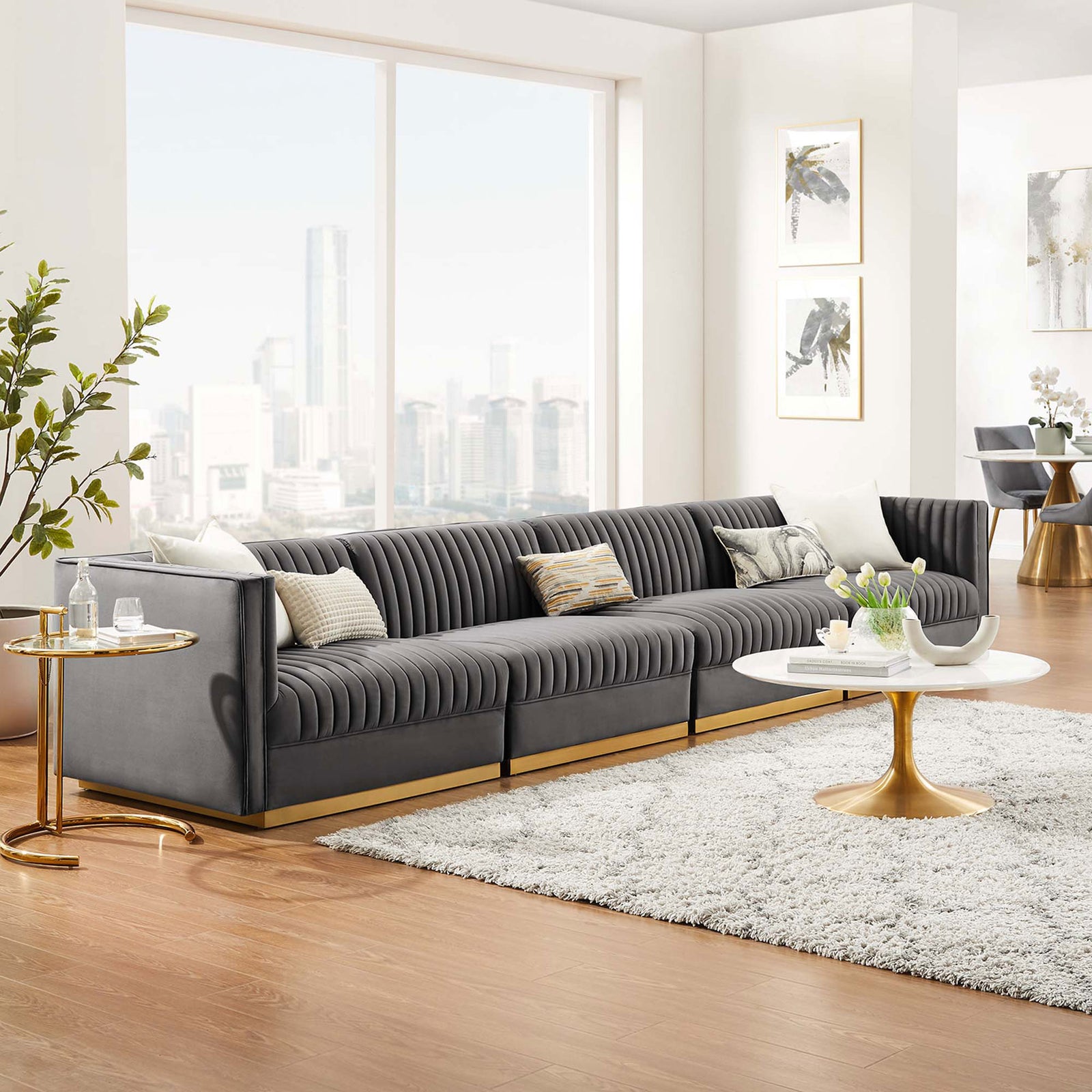 Luxurious gray velvet modular sectional with channel tufting and gold base anchored by a plush rug and round table || EEI-5827-GRY || front_angle_room