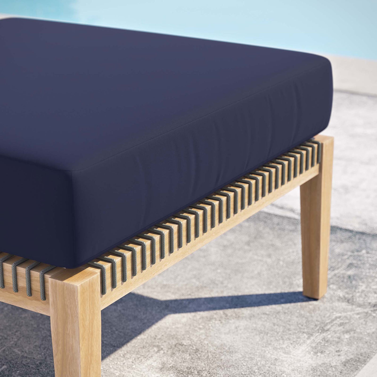 Navy cushion teak ottoman beside a shimmering pool, emphasizing its outdoor ready design || EEI-5854-GRY-NAV || detail_room