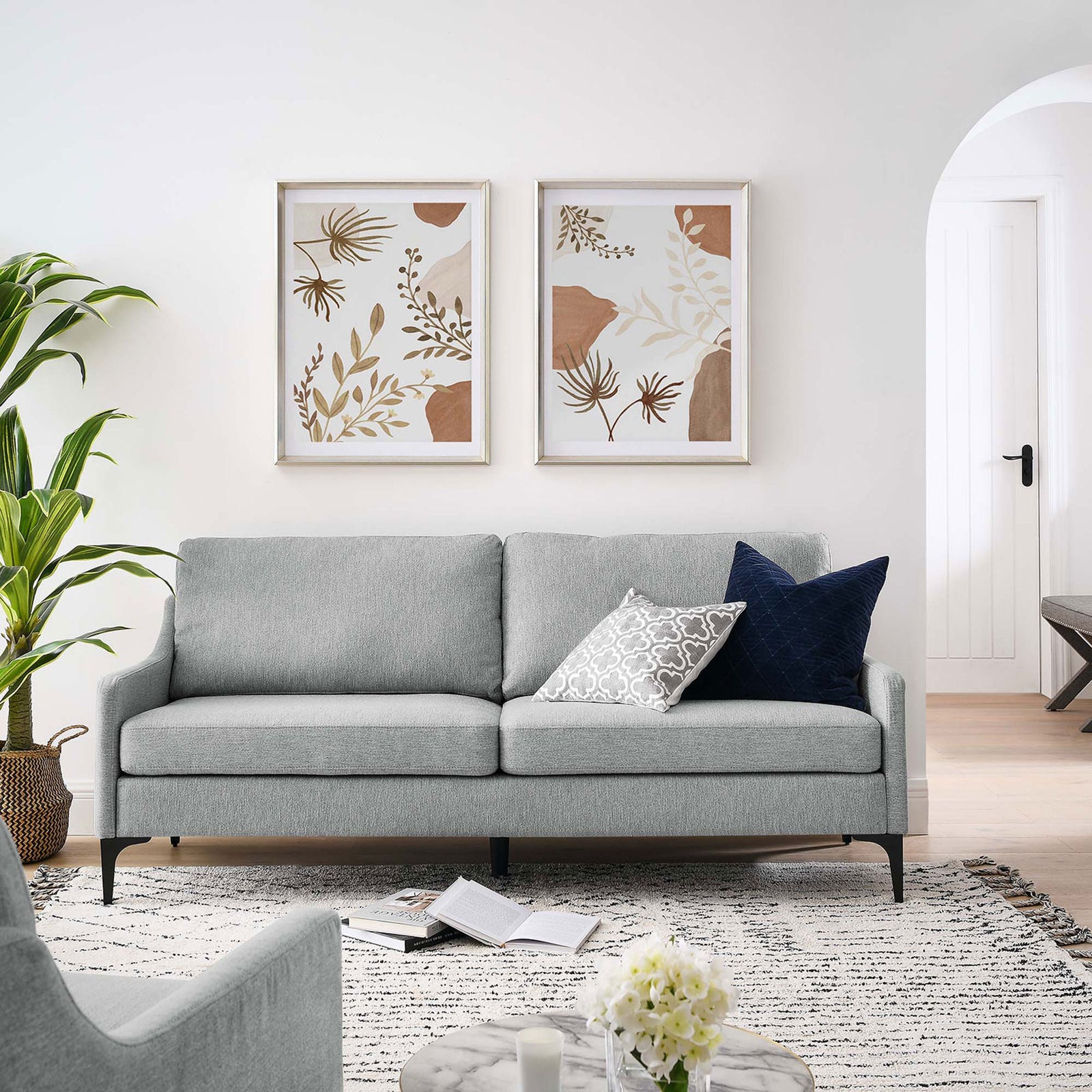 Light gray upholstered sofa in a bright living room with decorative pillows, artwork, and black metal legs || EEI-6019-LGR || front_room