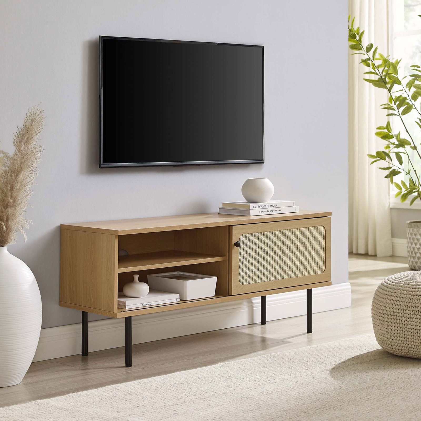 Oak TV console with rattan sliding door and black legs grounding a light, airy living space. || EEI-6044-OAK || front_angle_room