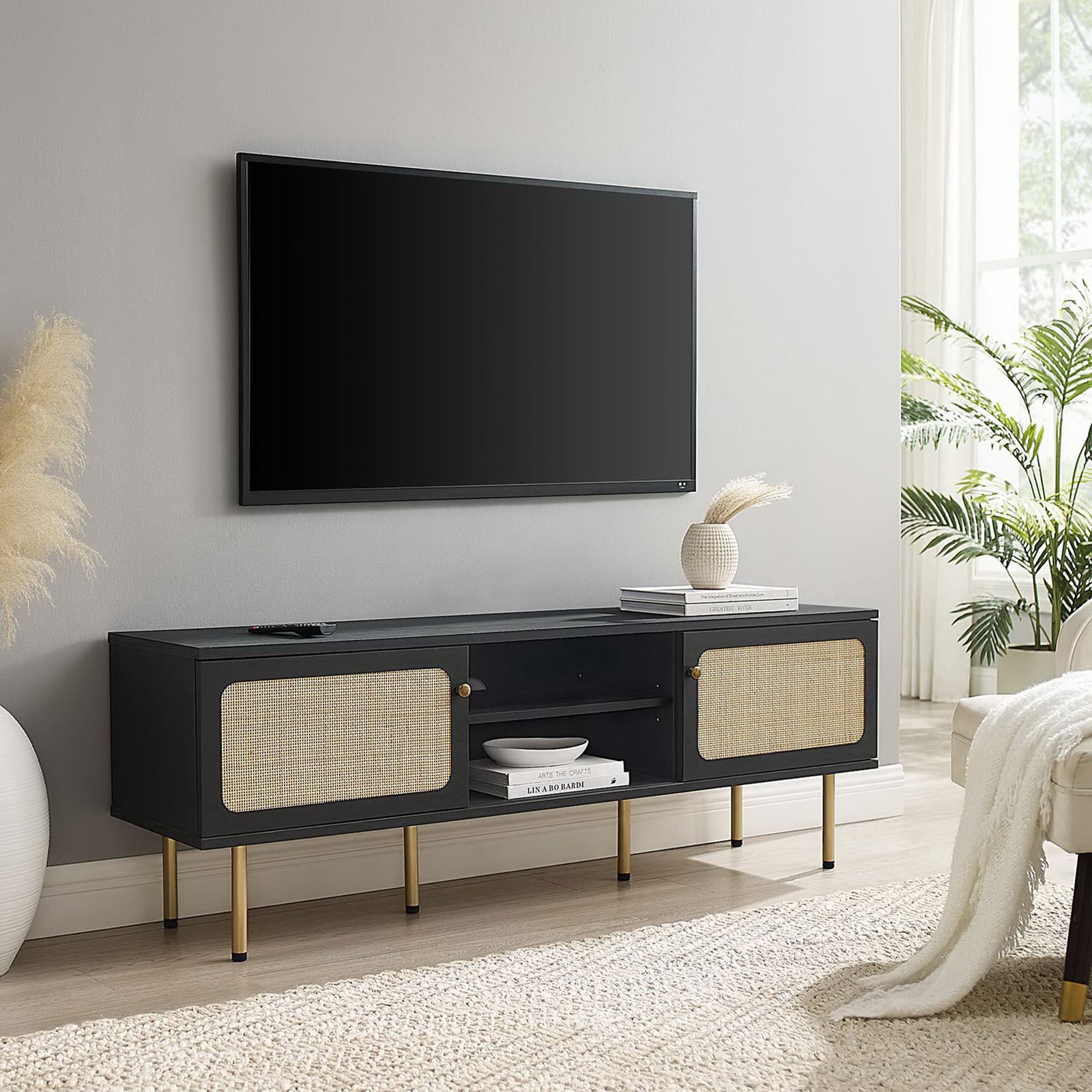 Black TV console with dual rattan doors and gold legs anchoring a bright, modern living room. || EEI-6045-BLK || front_angle_room