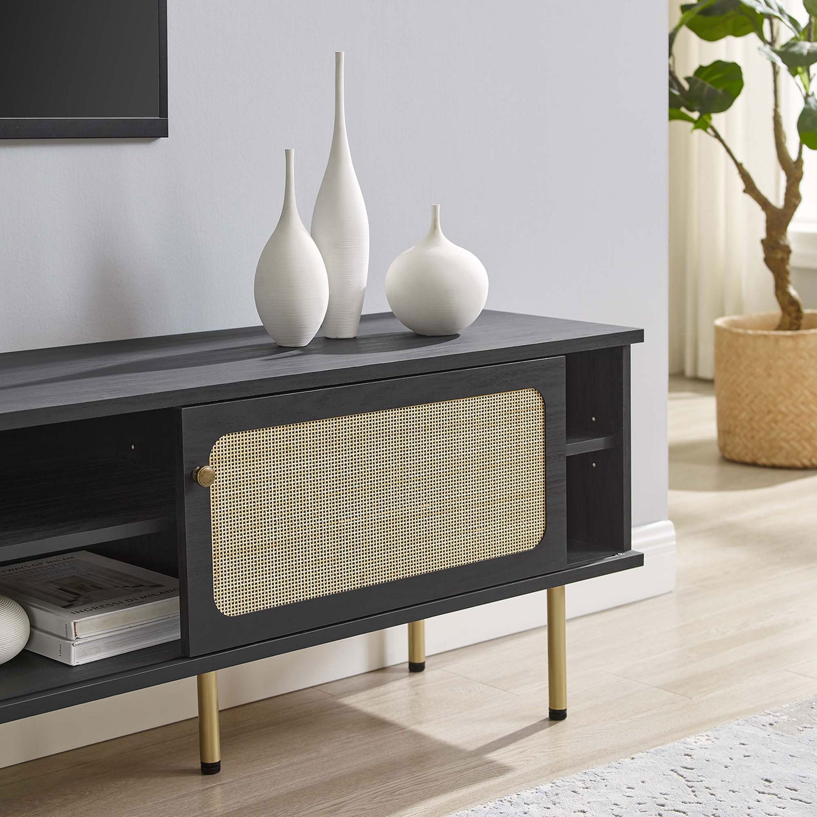 Black rattan TV stand stretching beneath a wall-mounted TV with vases and decor in a neutral room. || EEI-6046-BLK || storage_room