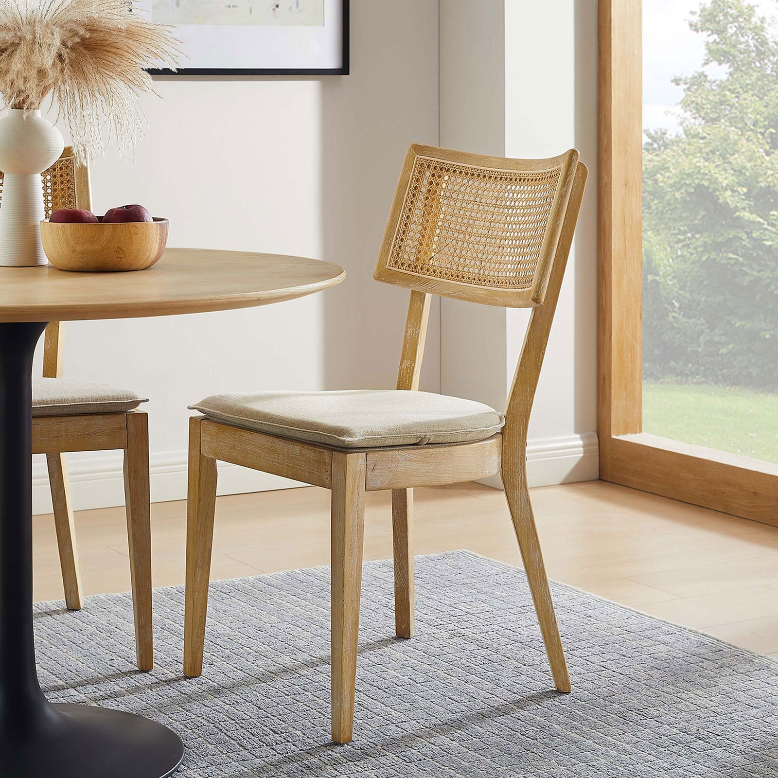 Gray beige upholstered dining chair beside a round wood table in a bright modern dining room || EEI-6080-GRY-BEI || front_angle_room