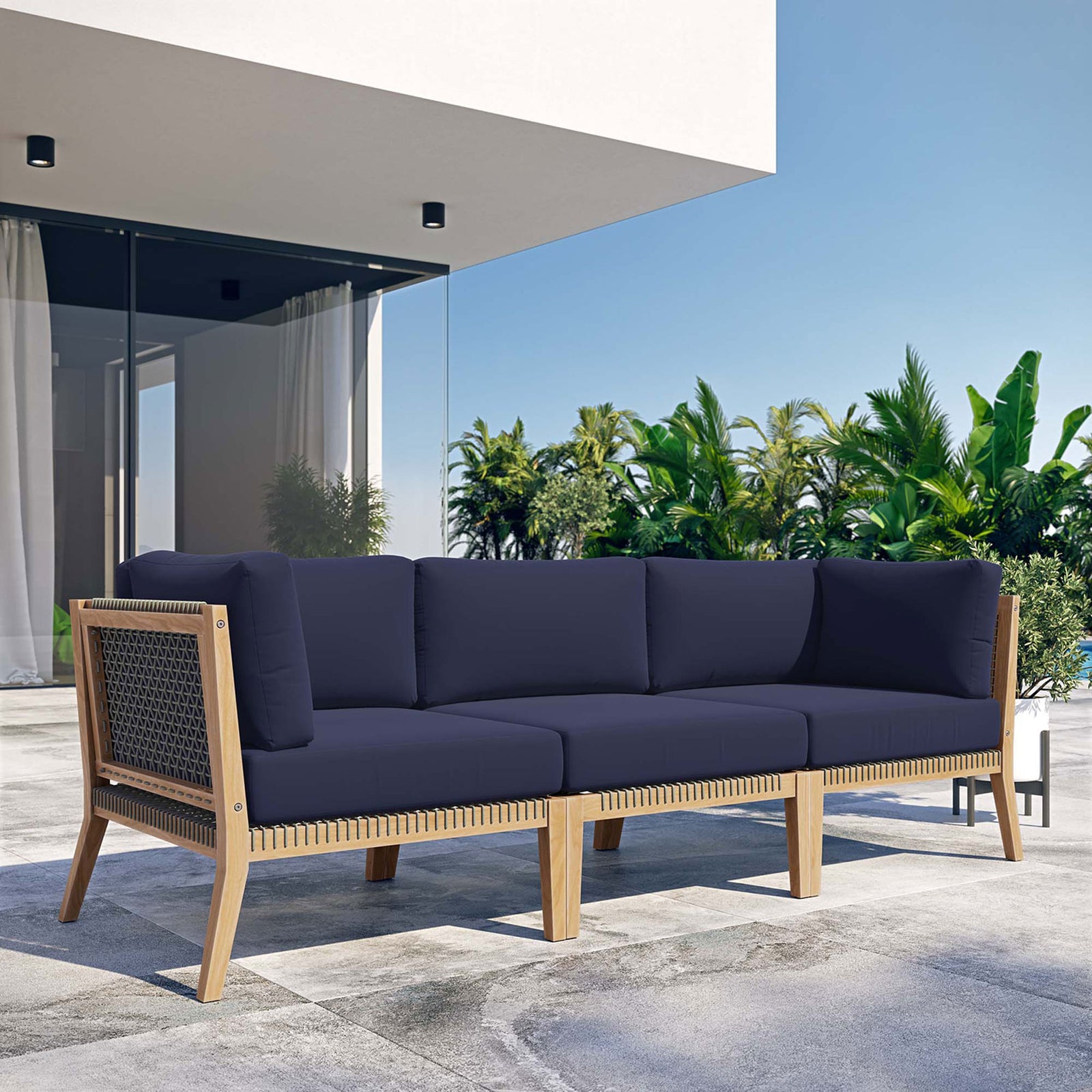 Navy blue teak outdoor sofa creating a modern lounge on a sunny patio || EEI-6120-GRY-NAV || front_angle_room